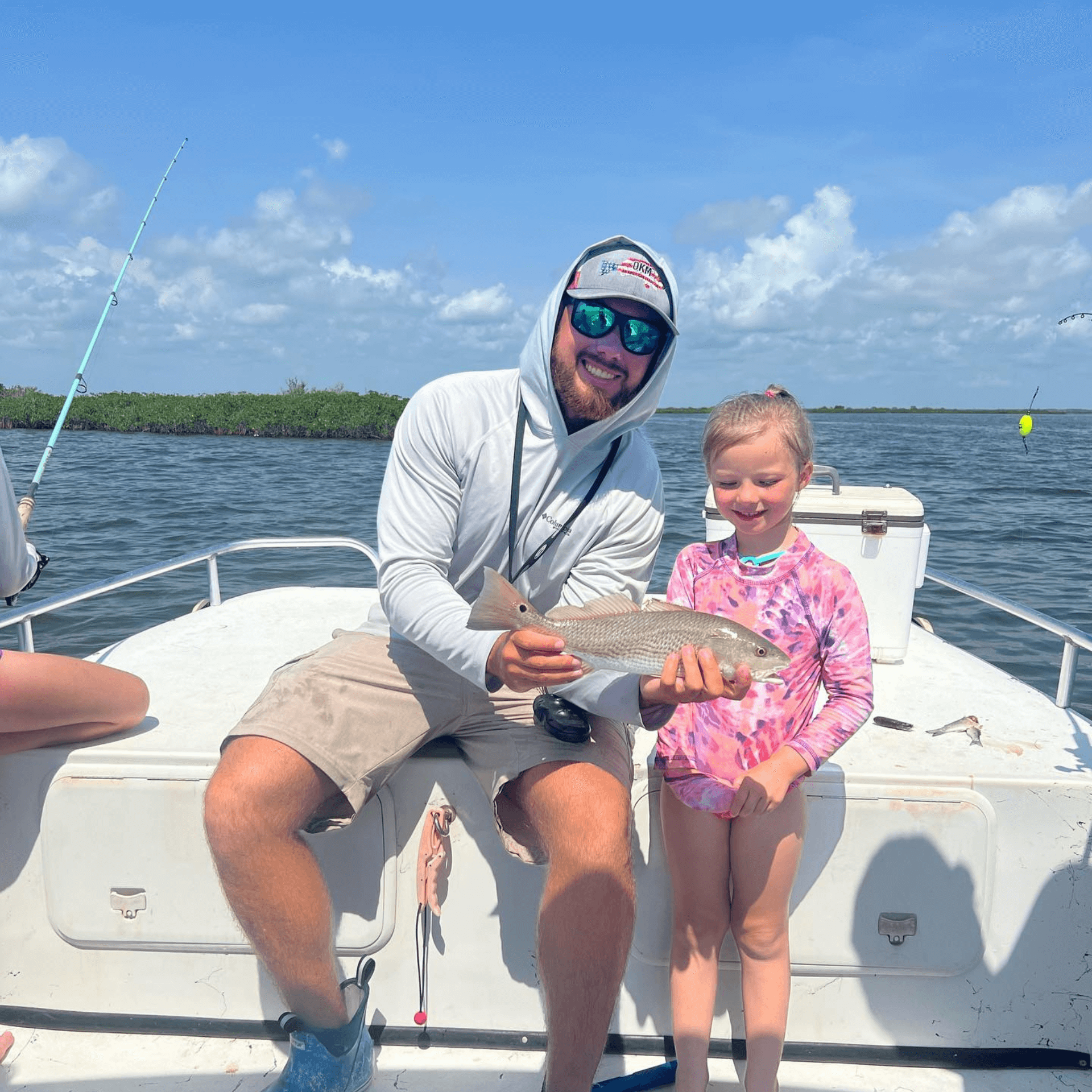A man and a little girl are sitting on a boat holding a fish.
