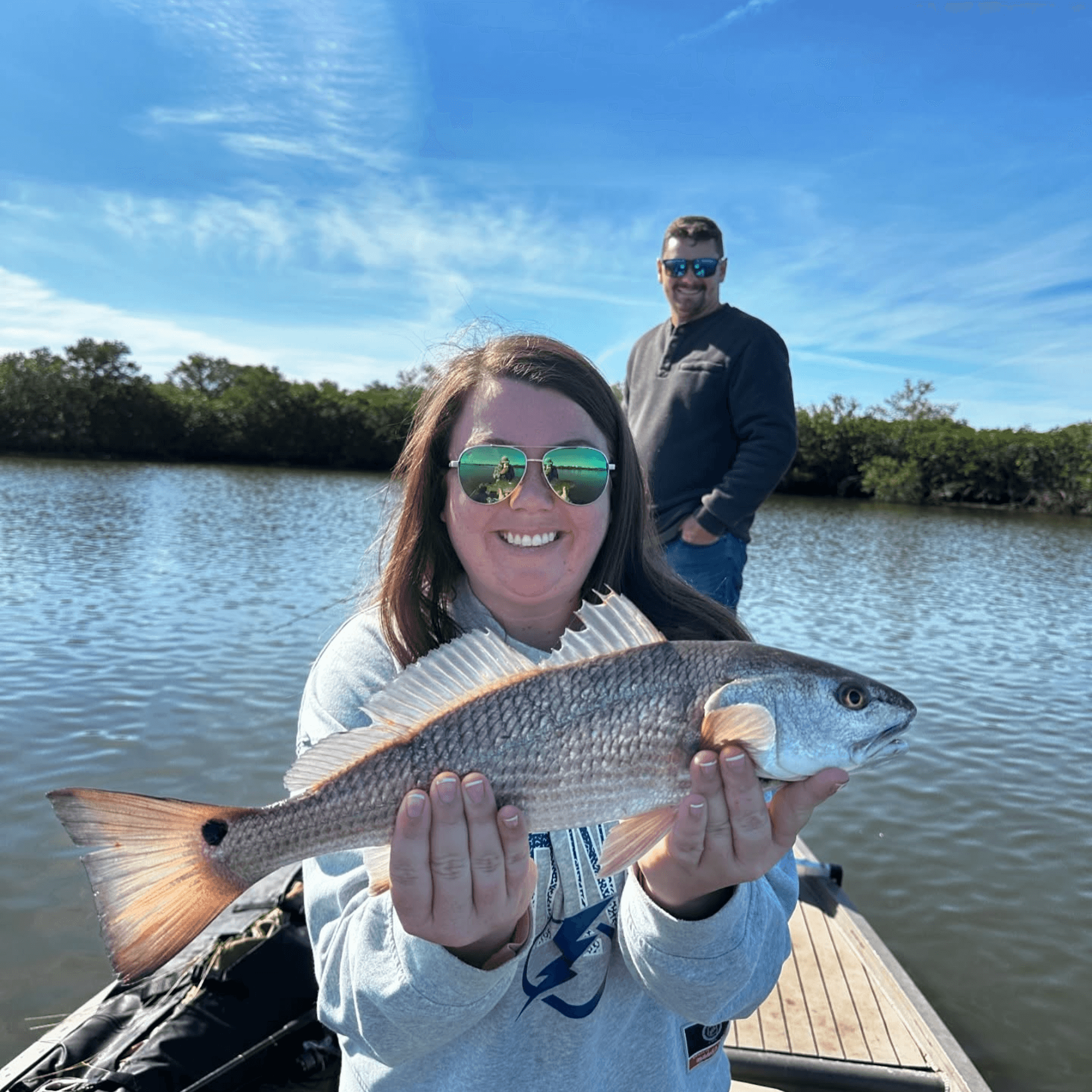 A woman is holding a fish in her hands on a boat.