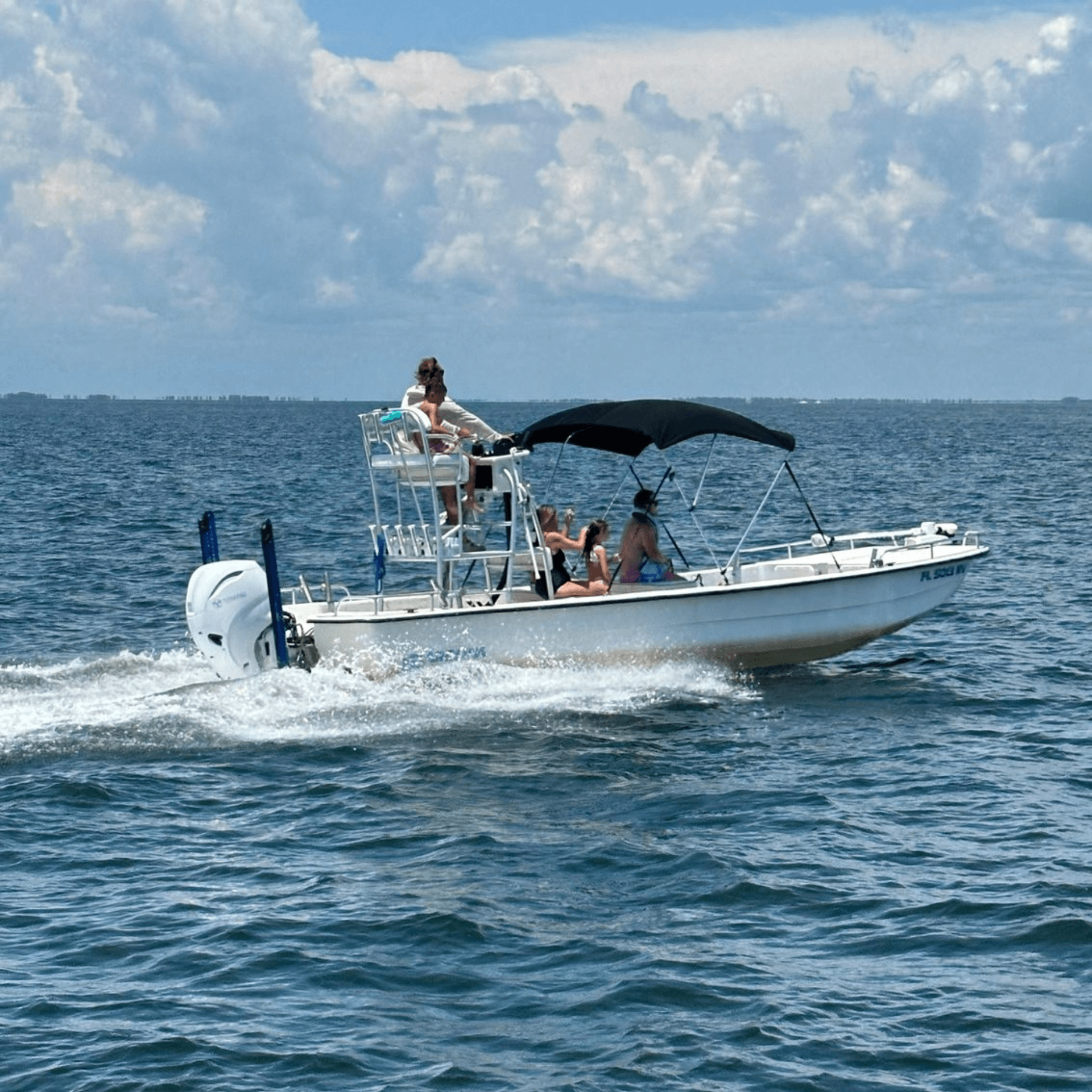 A boat with people on it is floating on top of a body of water.