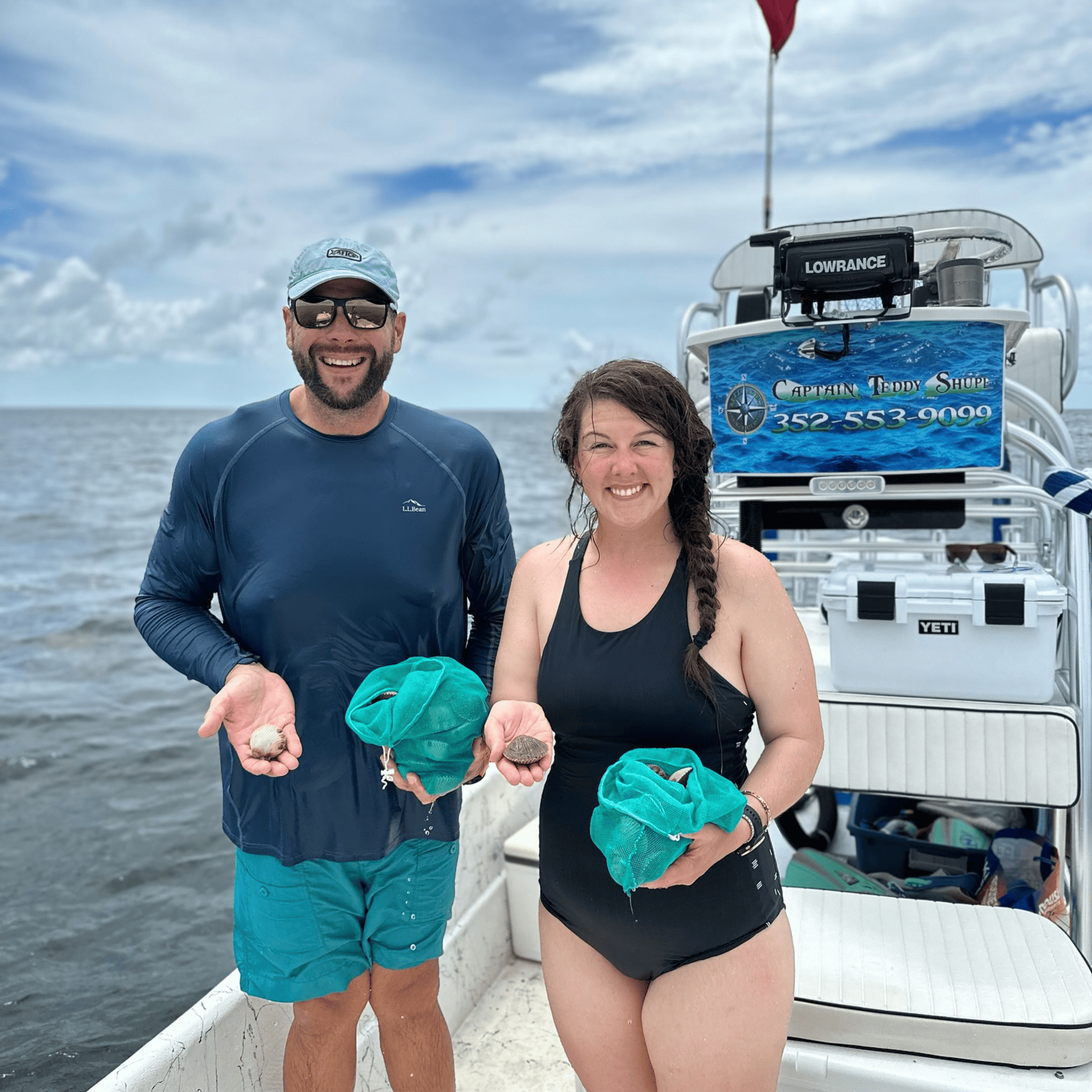 A man and a woman are standing on a boat holding crabs.