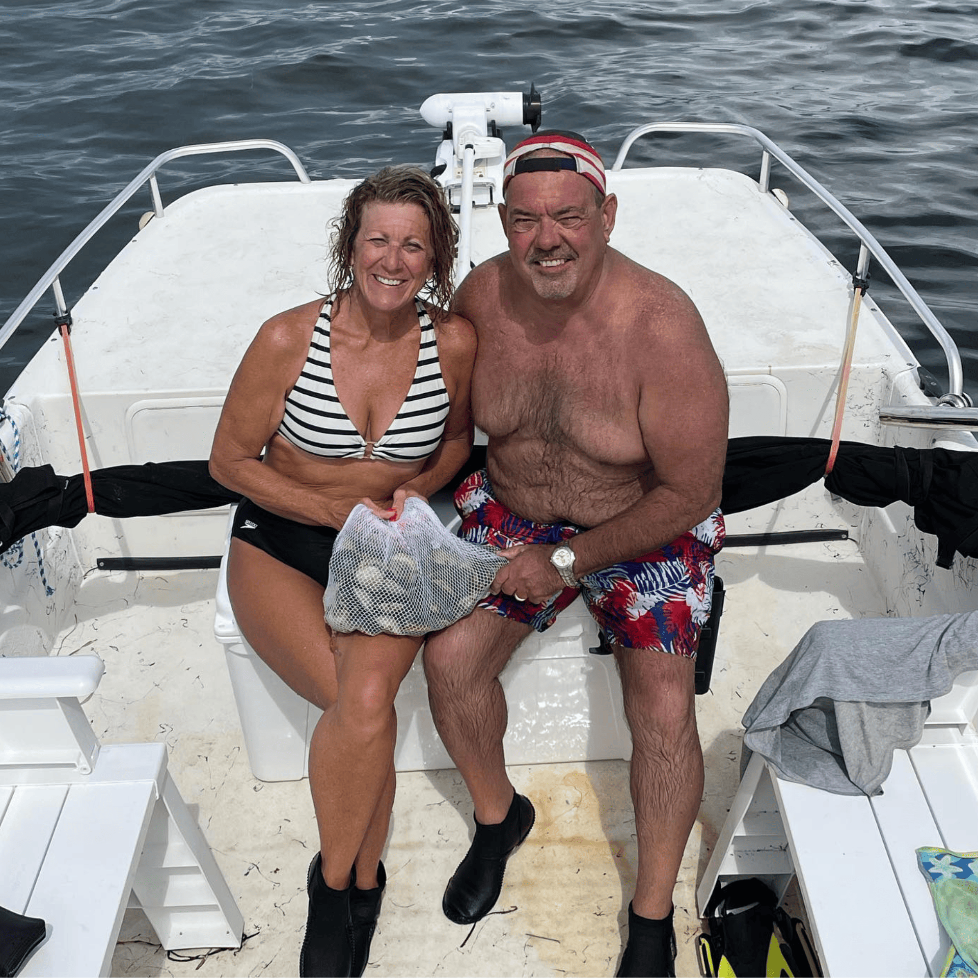 A man and a woman are sitting on the back of a boat with scallop harvets