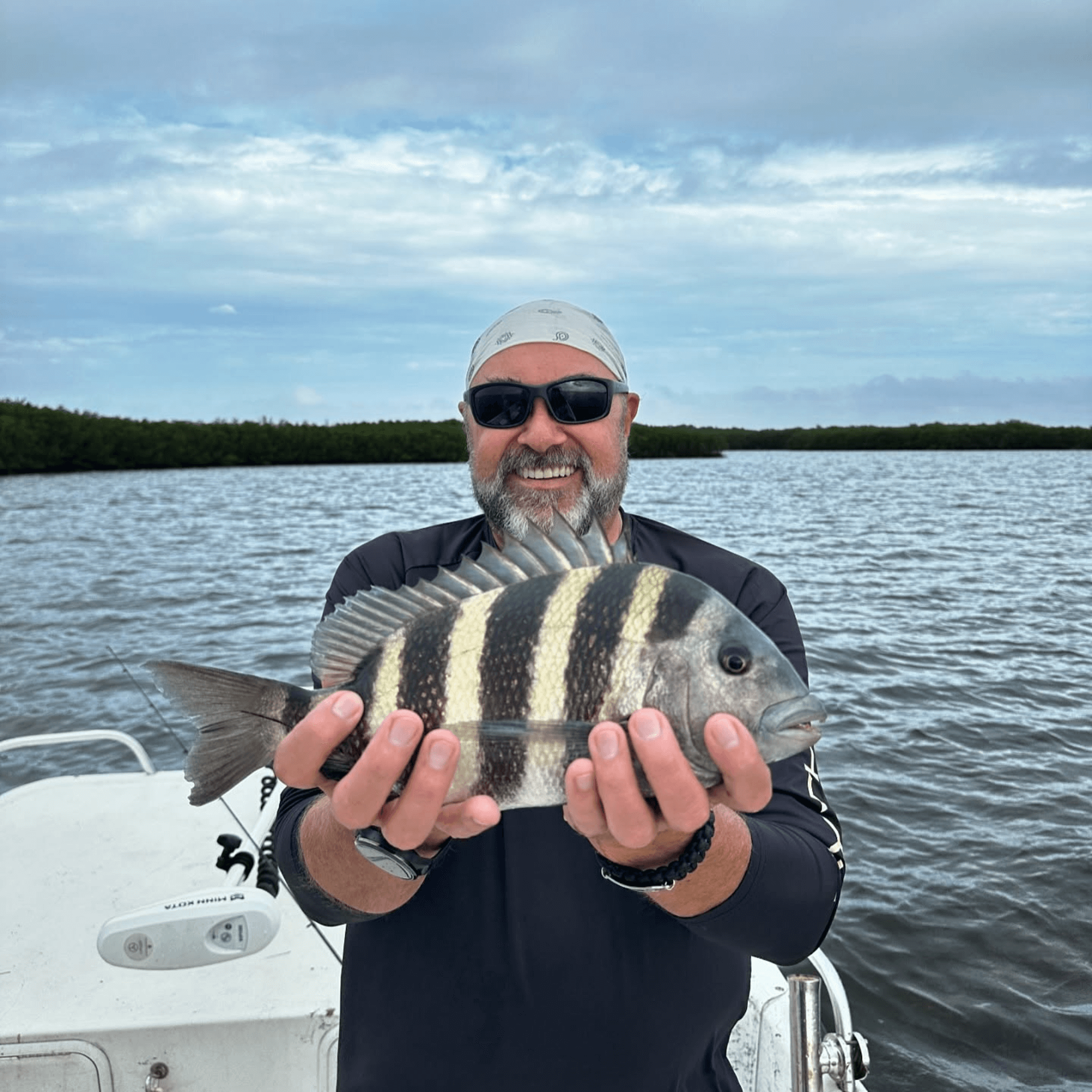 A man is holding a fish in his hands on a boat.