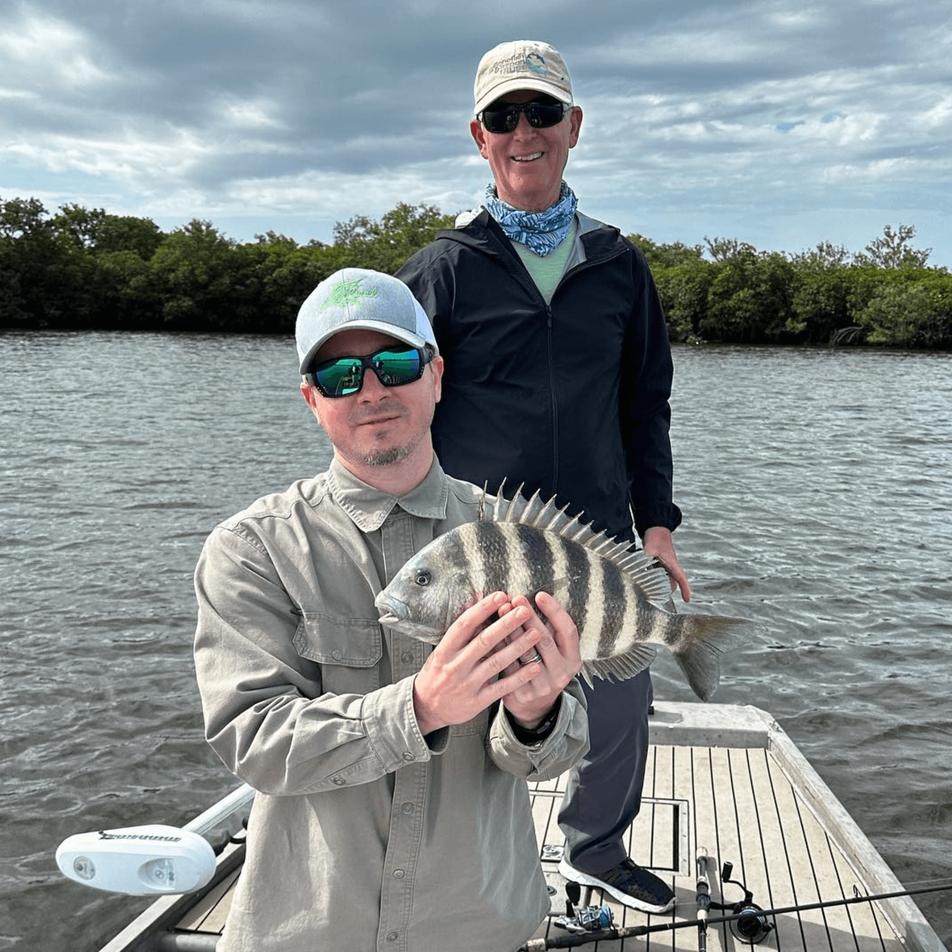 Two men are standing on a boat holding a fish.