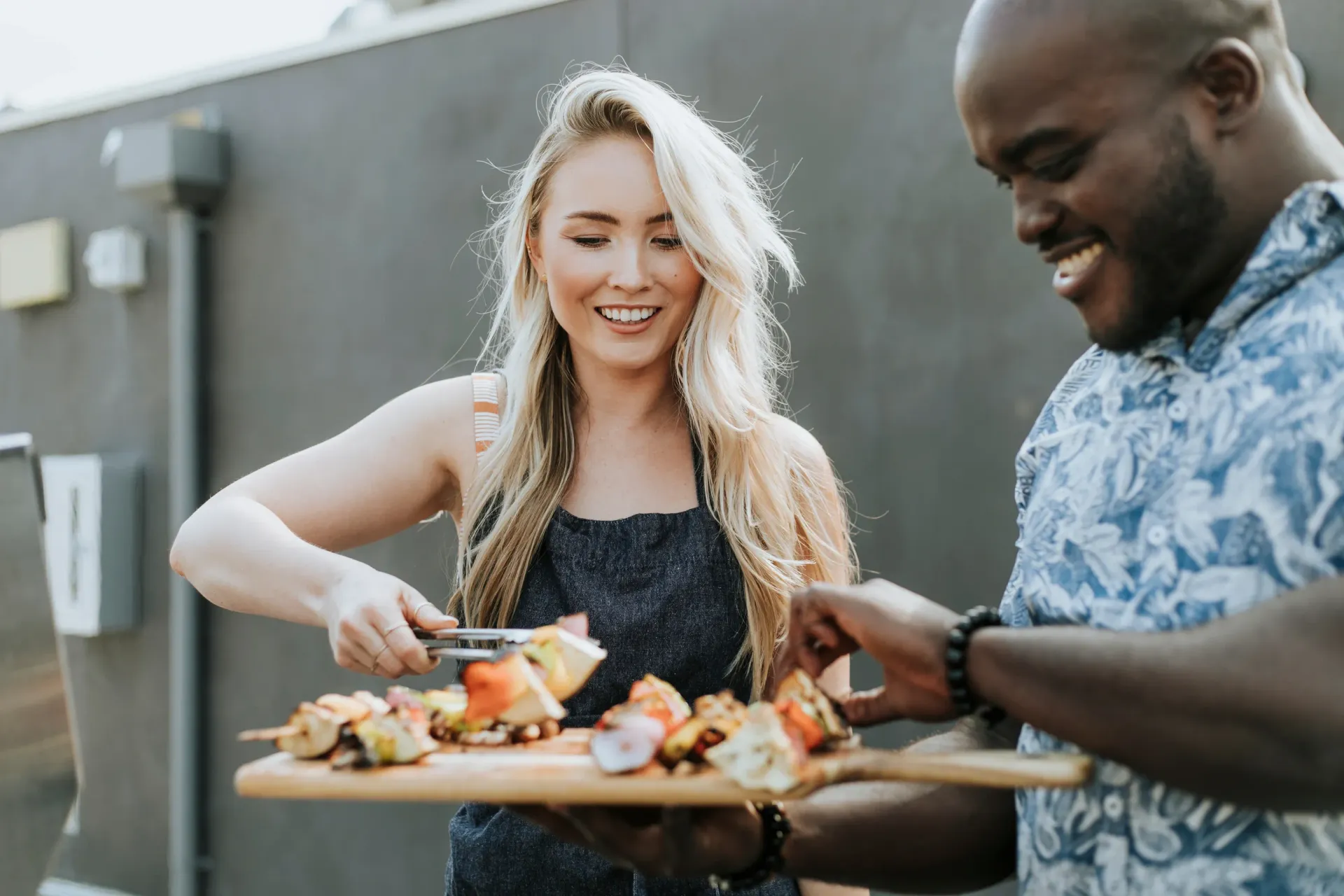 A man and a woman grilling food together outside.