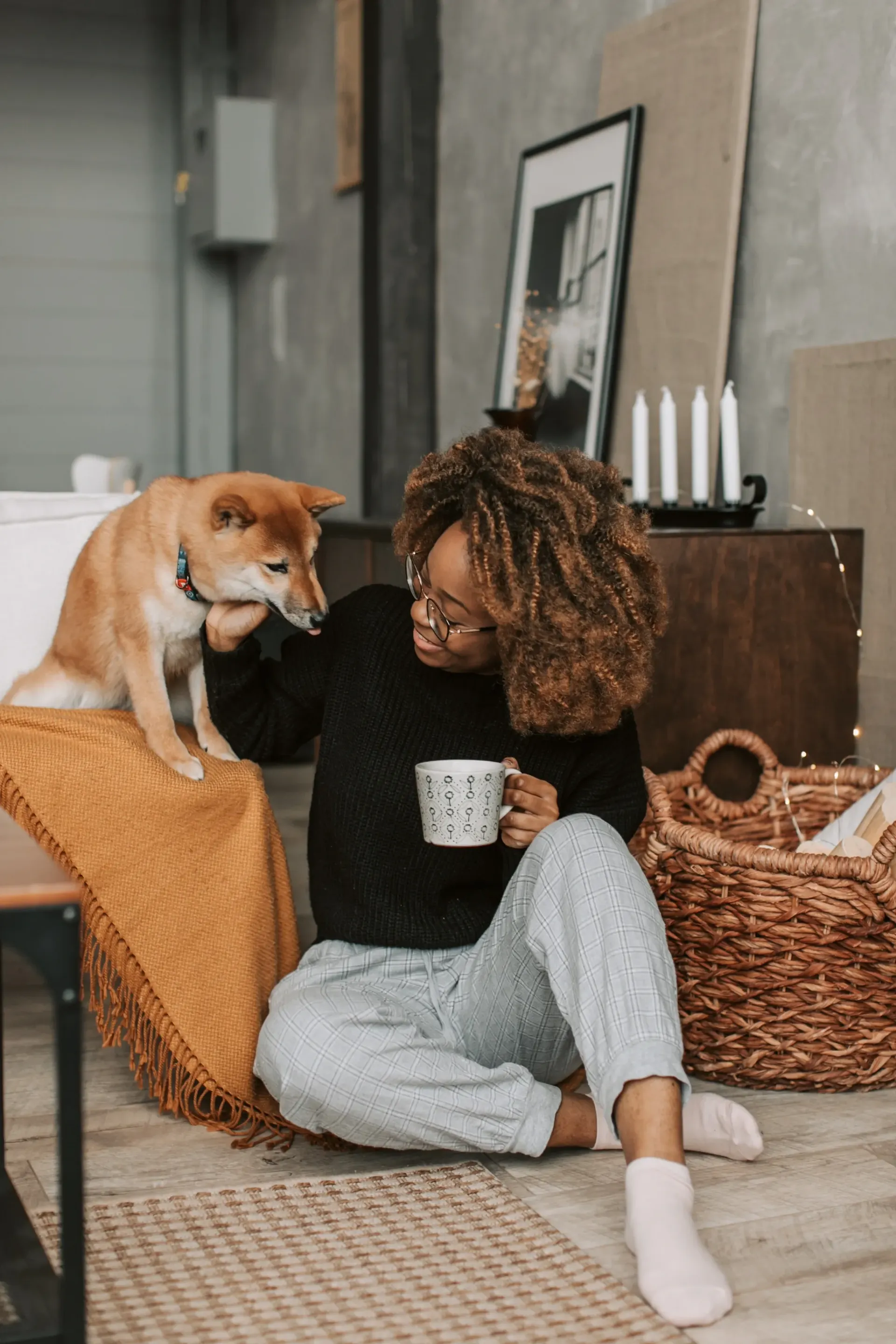 Woman holding a mug and petting her dog.
