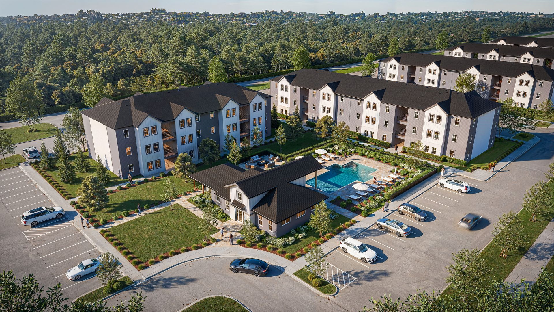 Aerial view of an apartment complex with a pool, parking lot, and surrounding trees