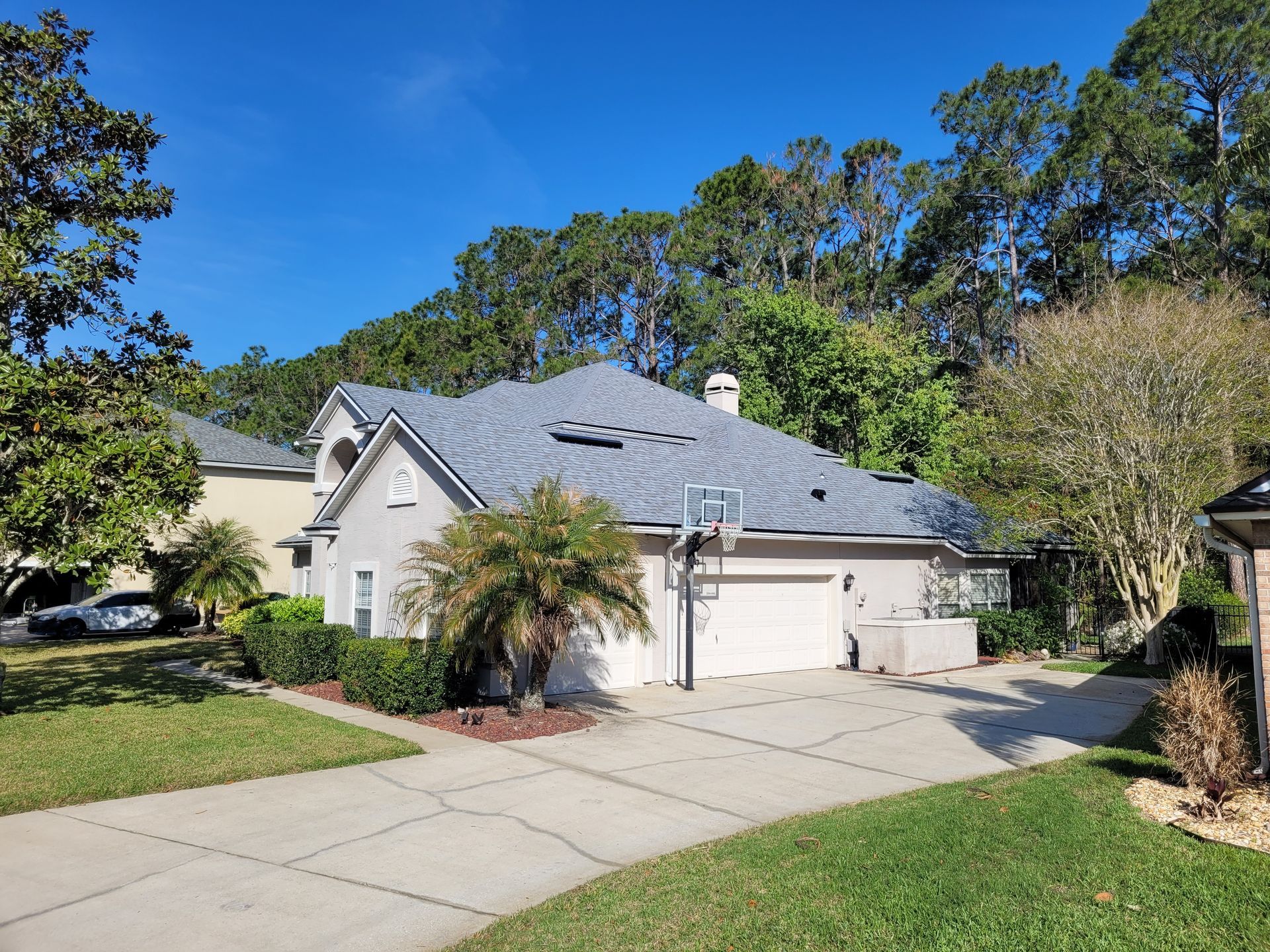 Suburban house with gray roof, two-car garage, and driveway under a clear blue sky