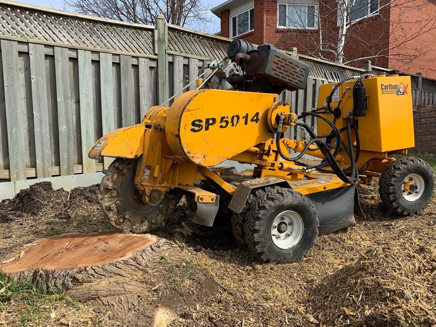 A yellow stump grinder sitting next to a tree stump