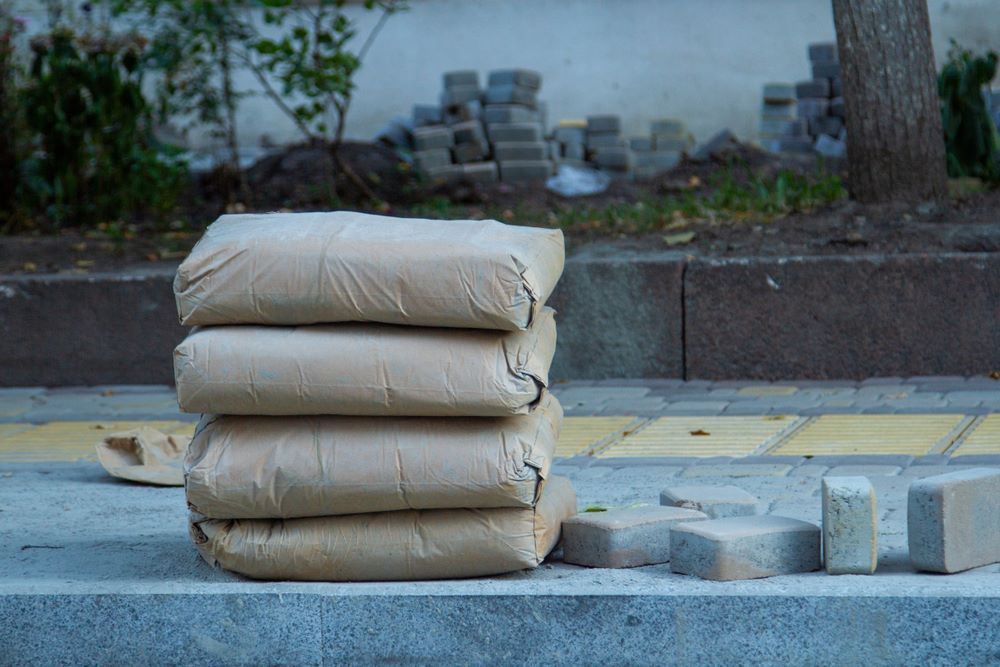Four Stacked Bags of Cement on A Concrete Curb — Cessnock Landscaping Supplies In Cessnock, NSW