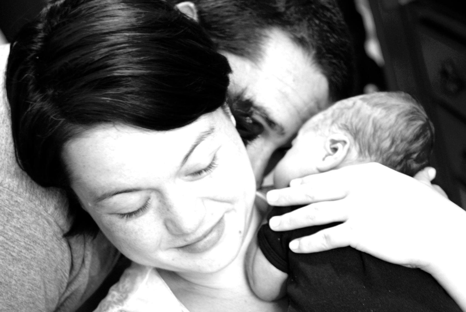 Woman smiling while holding a sleeping baby close to her face