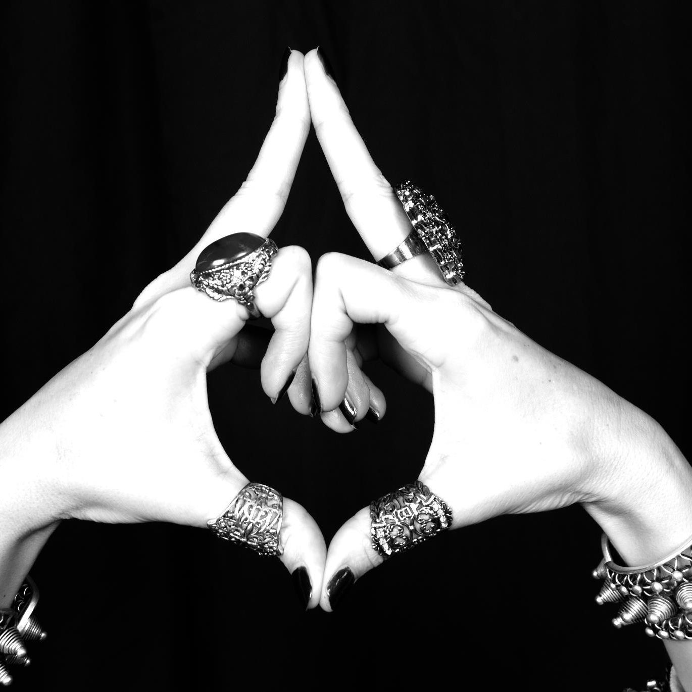 Black-and-white close-up of hands forming a heart shape with fingers and wrists adorned with jewelry