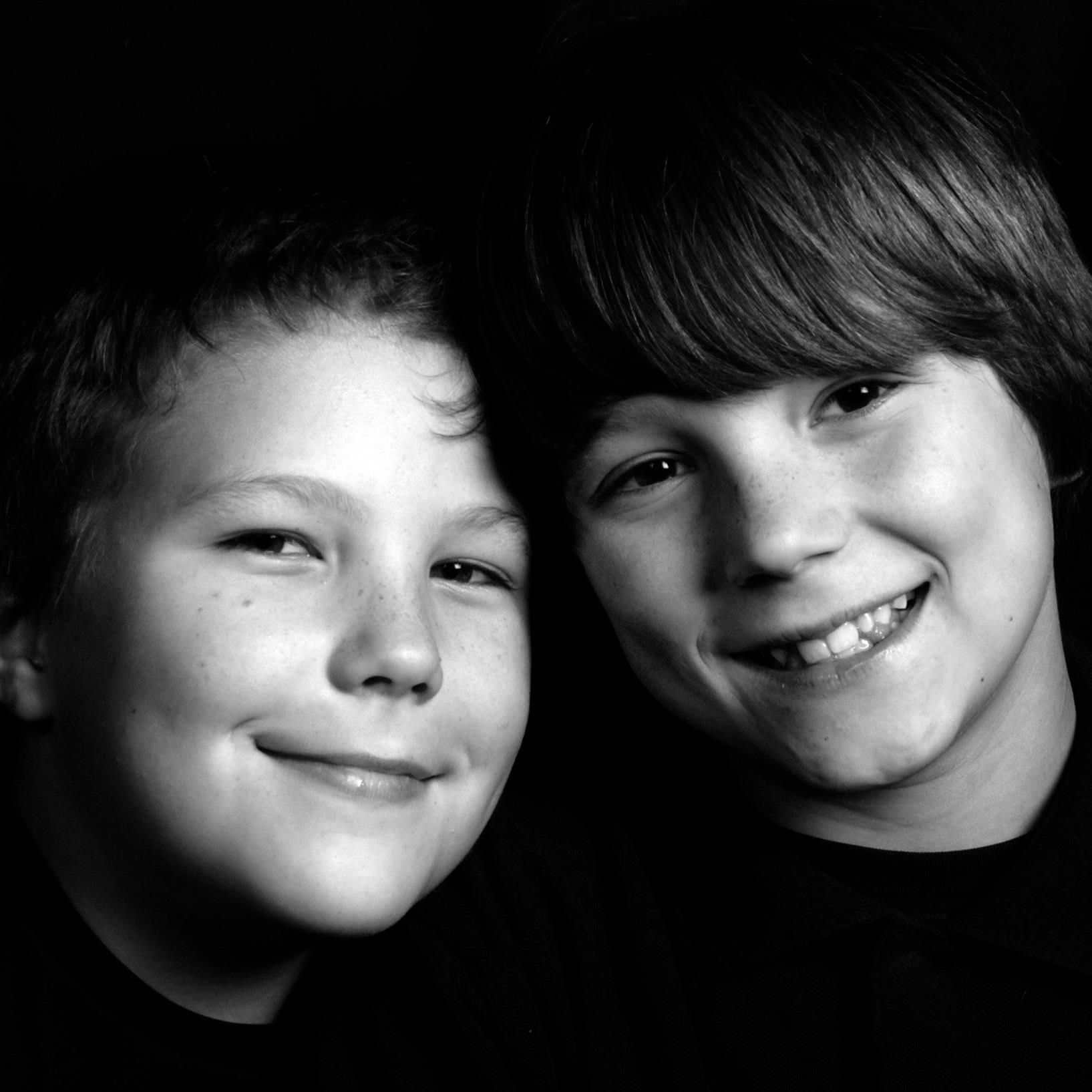 Two smiling children in black-and-white close-up portrait