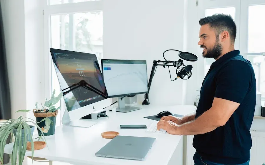 A man is standing at a standing desk in front of a computer.