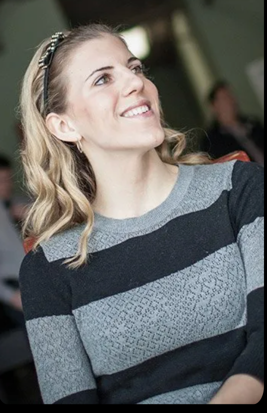A woman in a striped sweater is smiling and looking up.