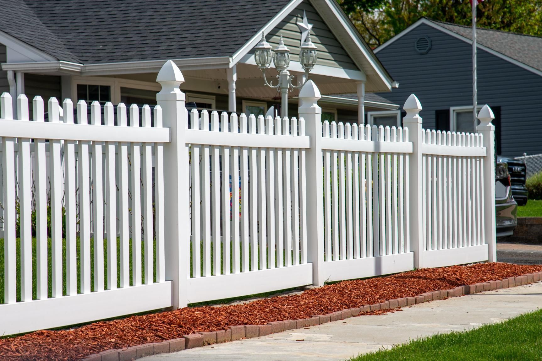 A white picket fence is in front of a house.