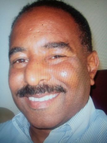 Professional headshot of man with mustache wearing light blue shirt