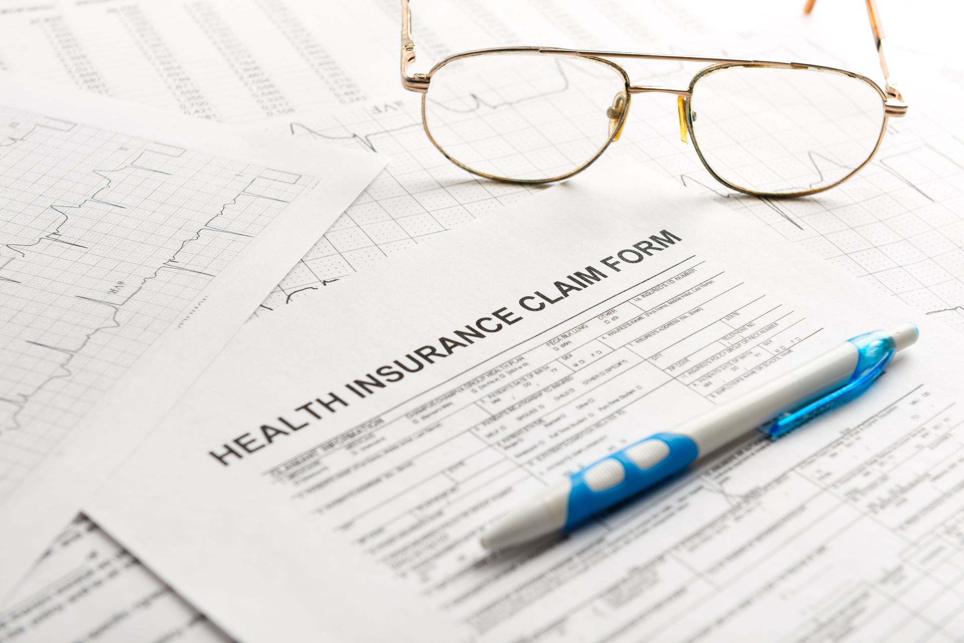 Medicare form with glasses & pen, isolated on white, clipping path ready.
