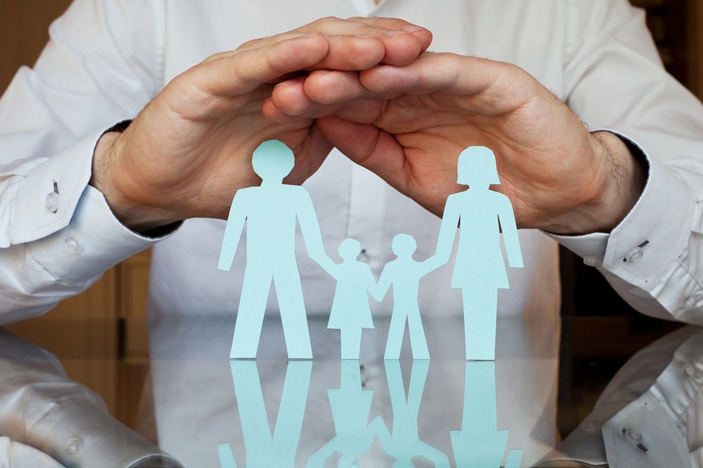 A man lifts paper cutouts of a family, reflecting the mission of McClure Insurance Agency and Brightstar Insurance.