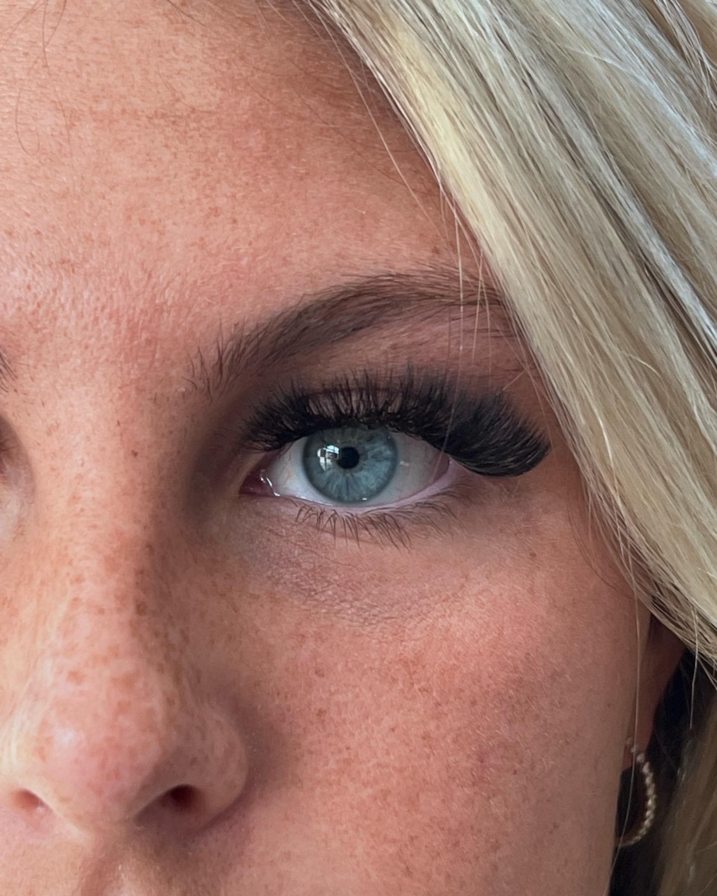 A close up of a woman 's blue eye with long eyelashes.