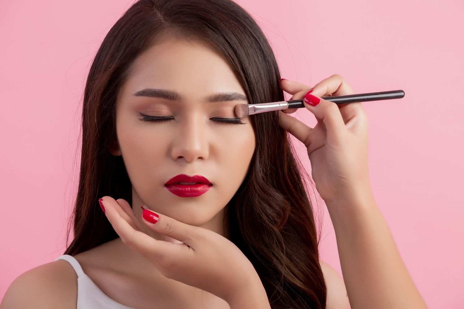 A woman is applying eye shadow to her eye with a brush.