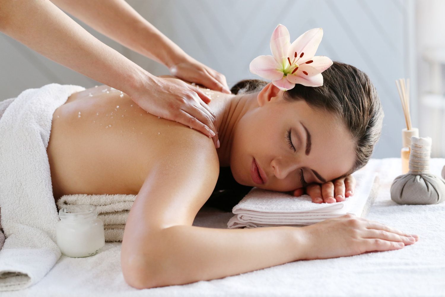 A woman is getting a massage at a spa with a flower in her hair.