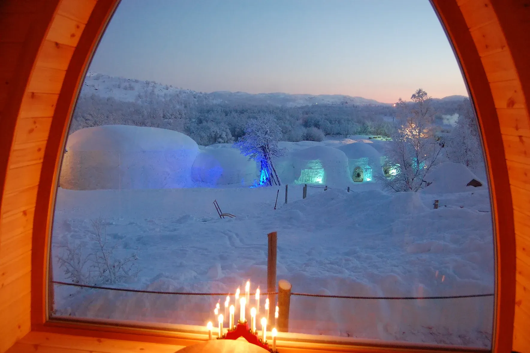 A window with a view of a snowy field with igloos in the background in Norway.