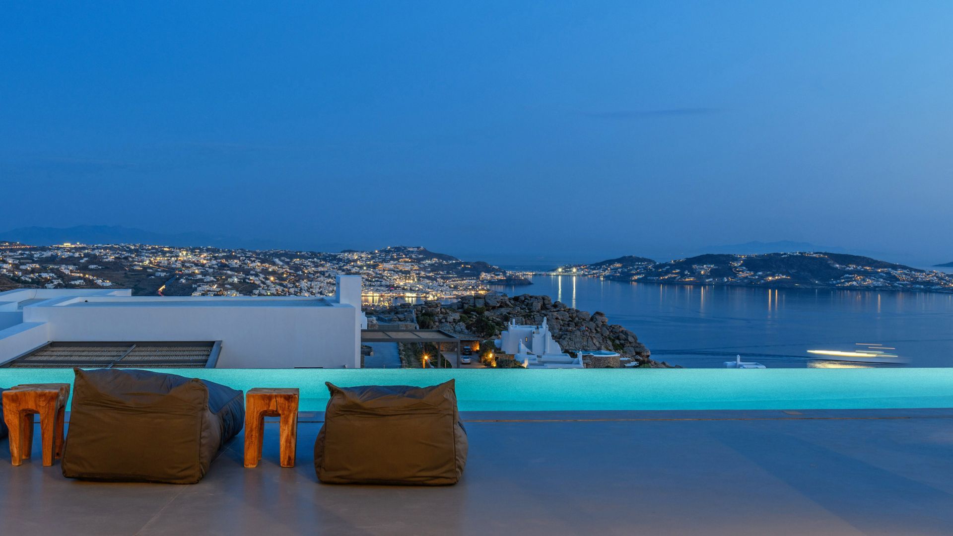 There is a swimming pool on the roof of a building overlooking the ocean at villa in Mykonos, Greece.
