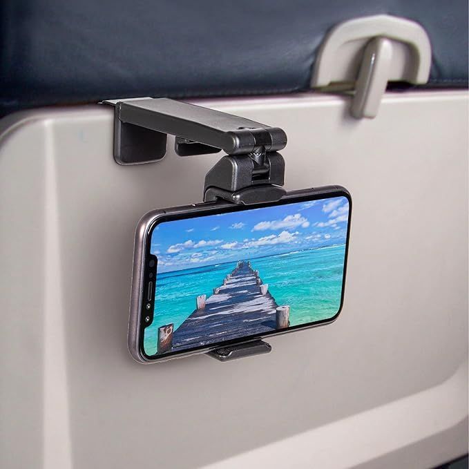 A cell phone is hanging from a holder on an airplane seat.