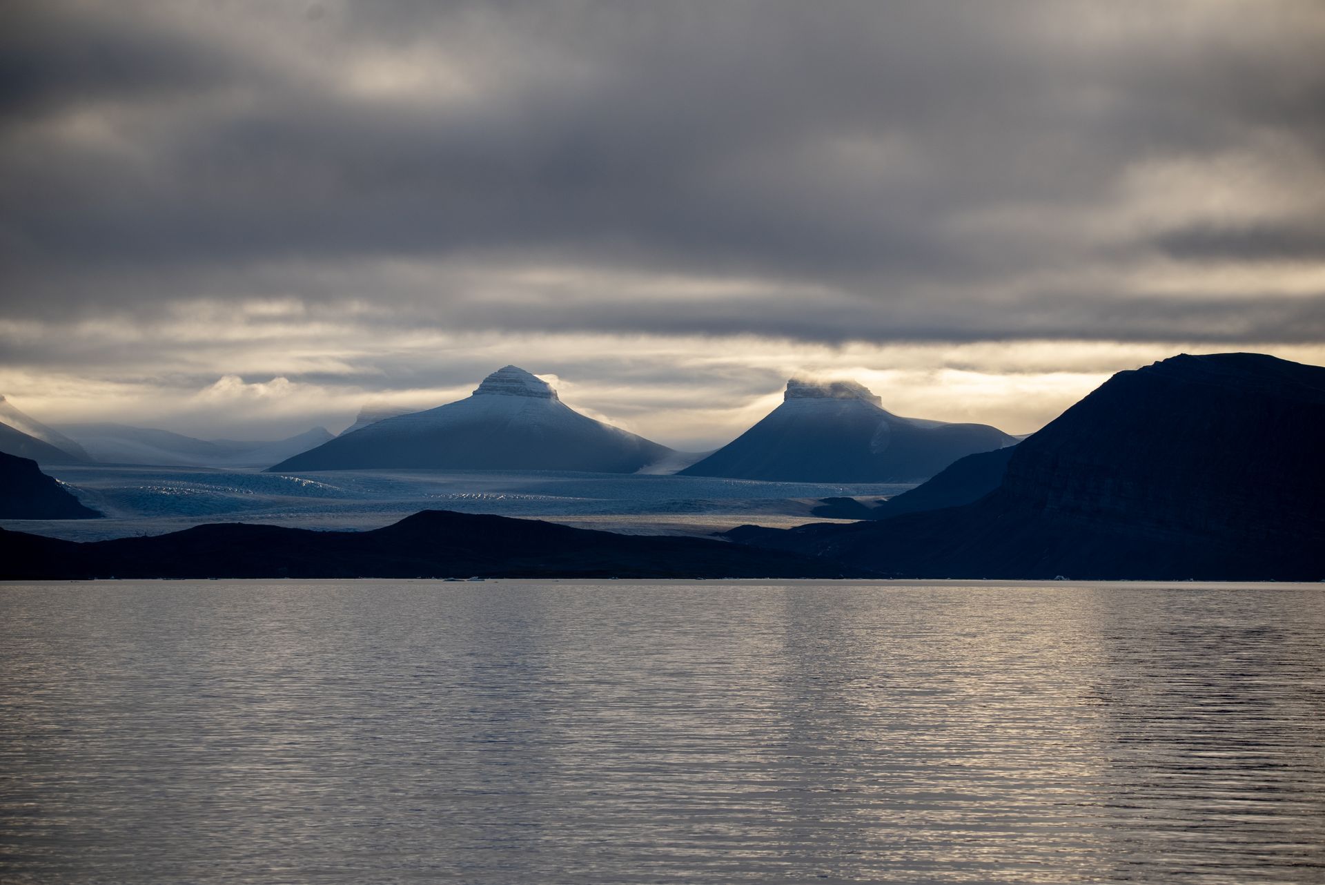 A lake with mountains in the background and a cloudy sky