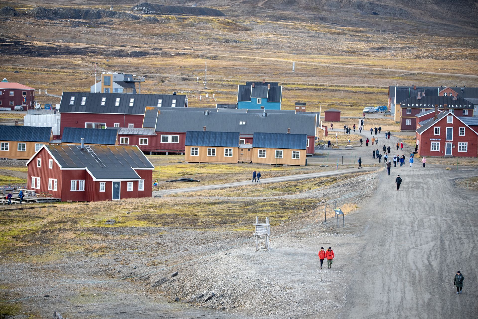 A group of people are walking down a dirt road in a small town