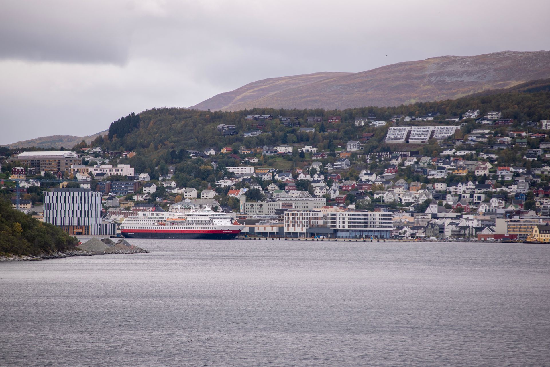 A large body of water with a city in the background and a Hurtigruten cruise ship in Svalbard.