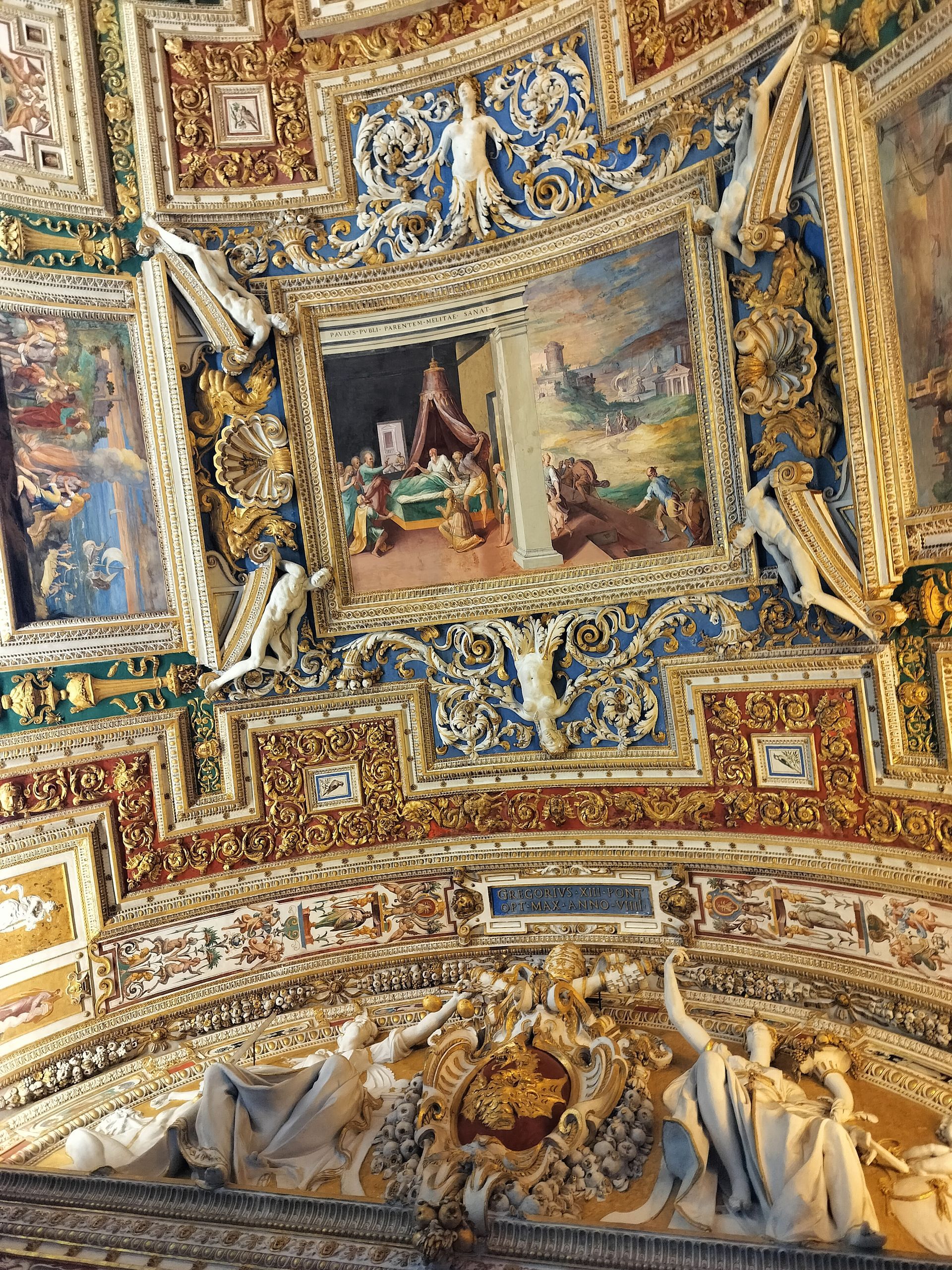 Ornate, painted ceiling with biblical scenes, sculptures, and gold accents.