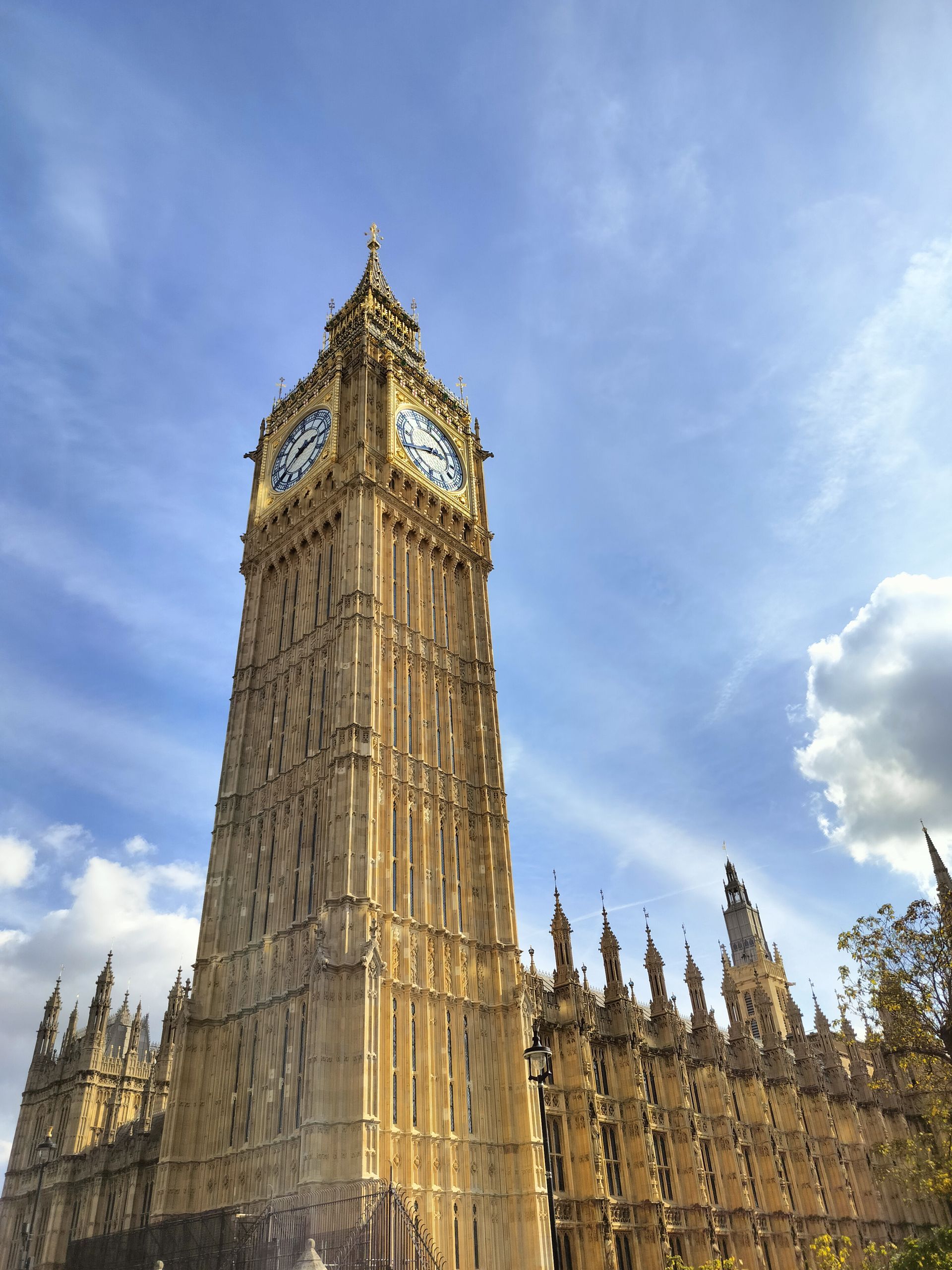 Big Ben clock tower, London, England, against a blue sky with fluffy clouds.