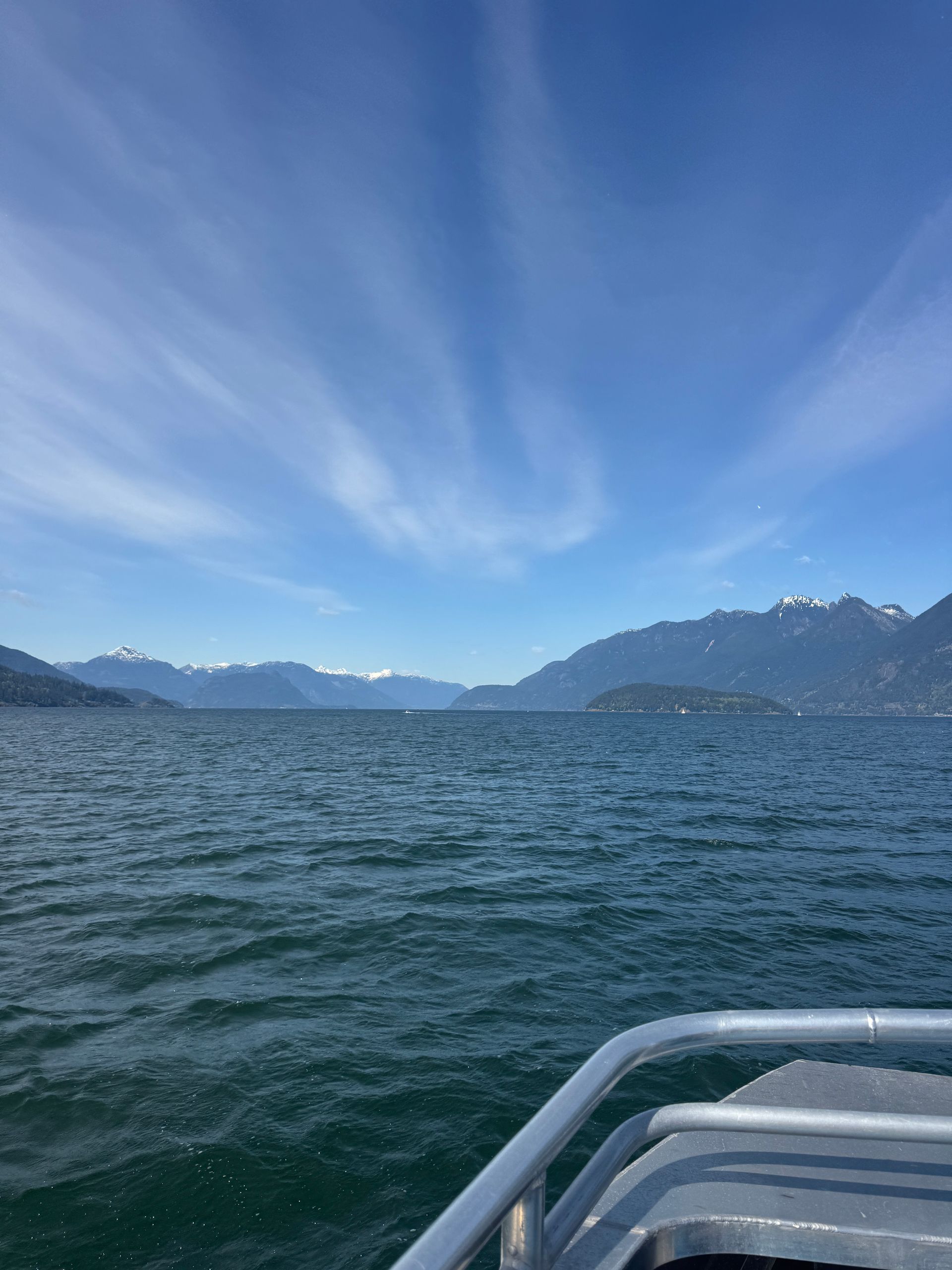 Choppy blue lake with distant mountains under a clear sky, viewed from a boat bow