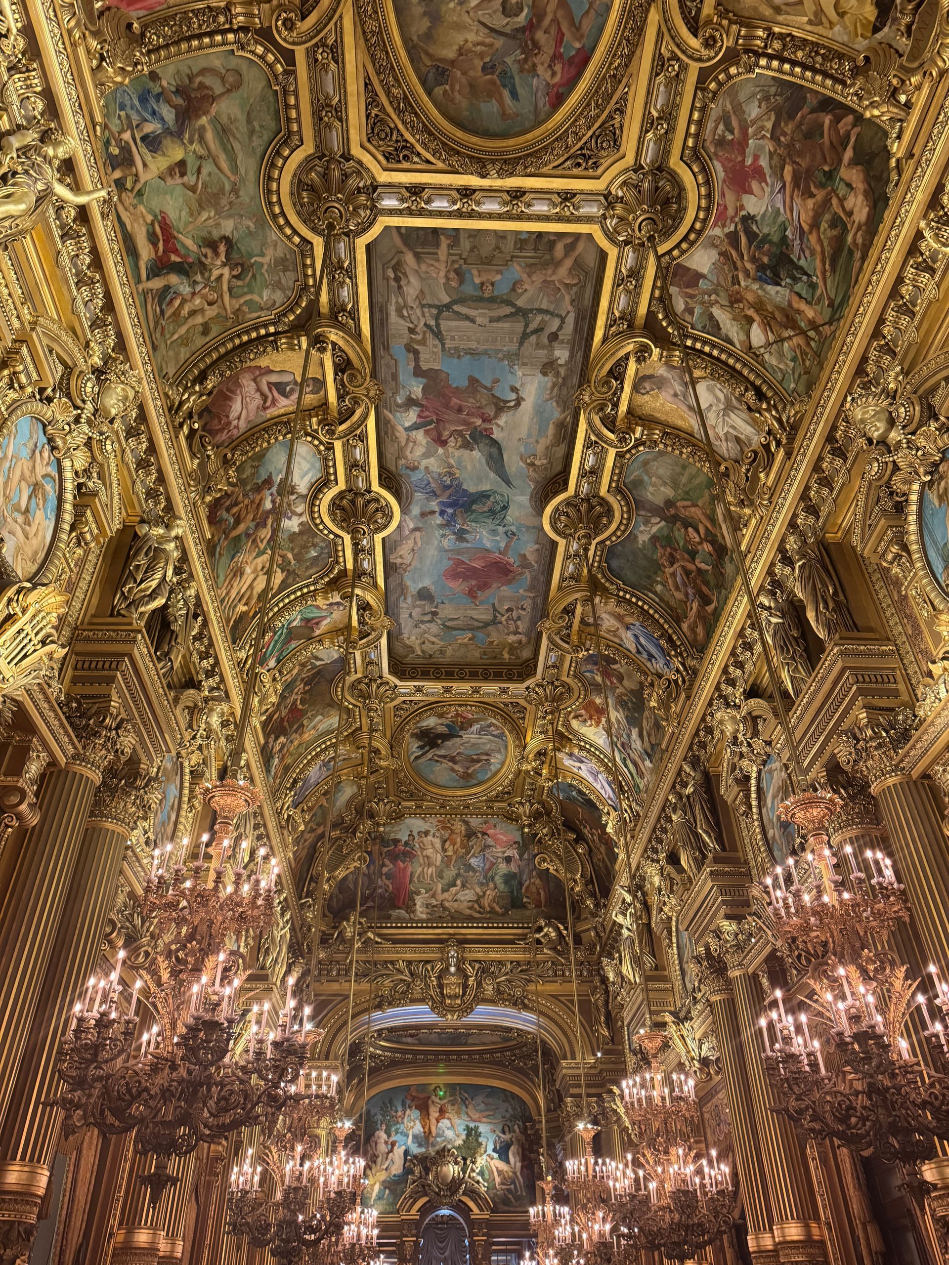 The ceiling of the Palais Garnier, with a lot of chandeliers and paintings on it in Paris, France.