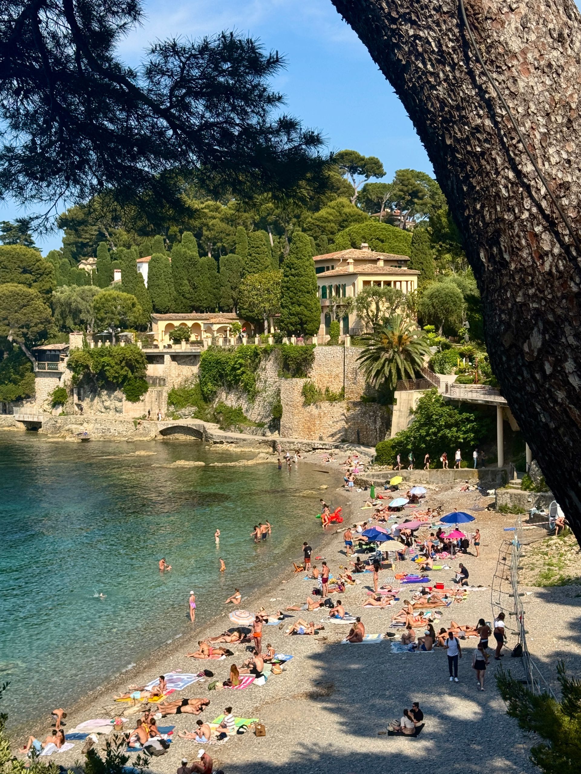 Plage Paloma with a lot of people on it and a house in the background in Saint-Jean-Cap-Ferrat, France.