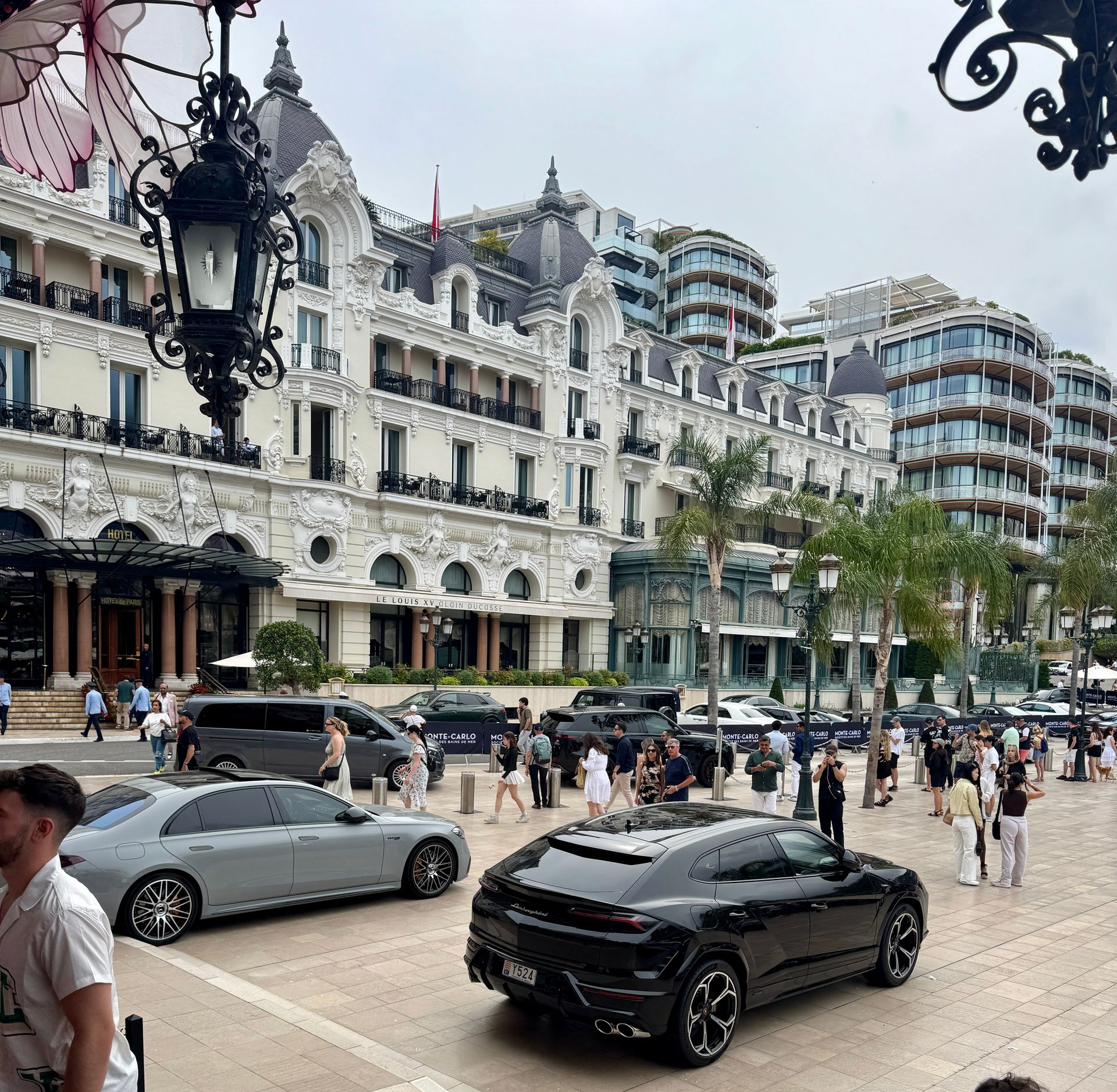 Luxurious buildings and parked cars in Monte Carlo, with people walking on the sidewalk.