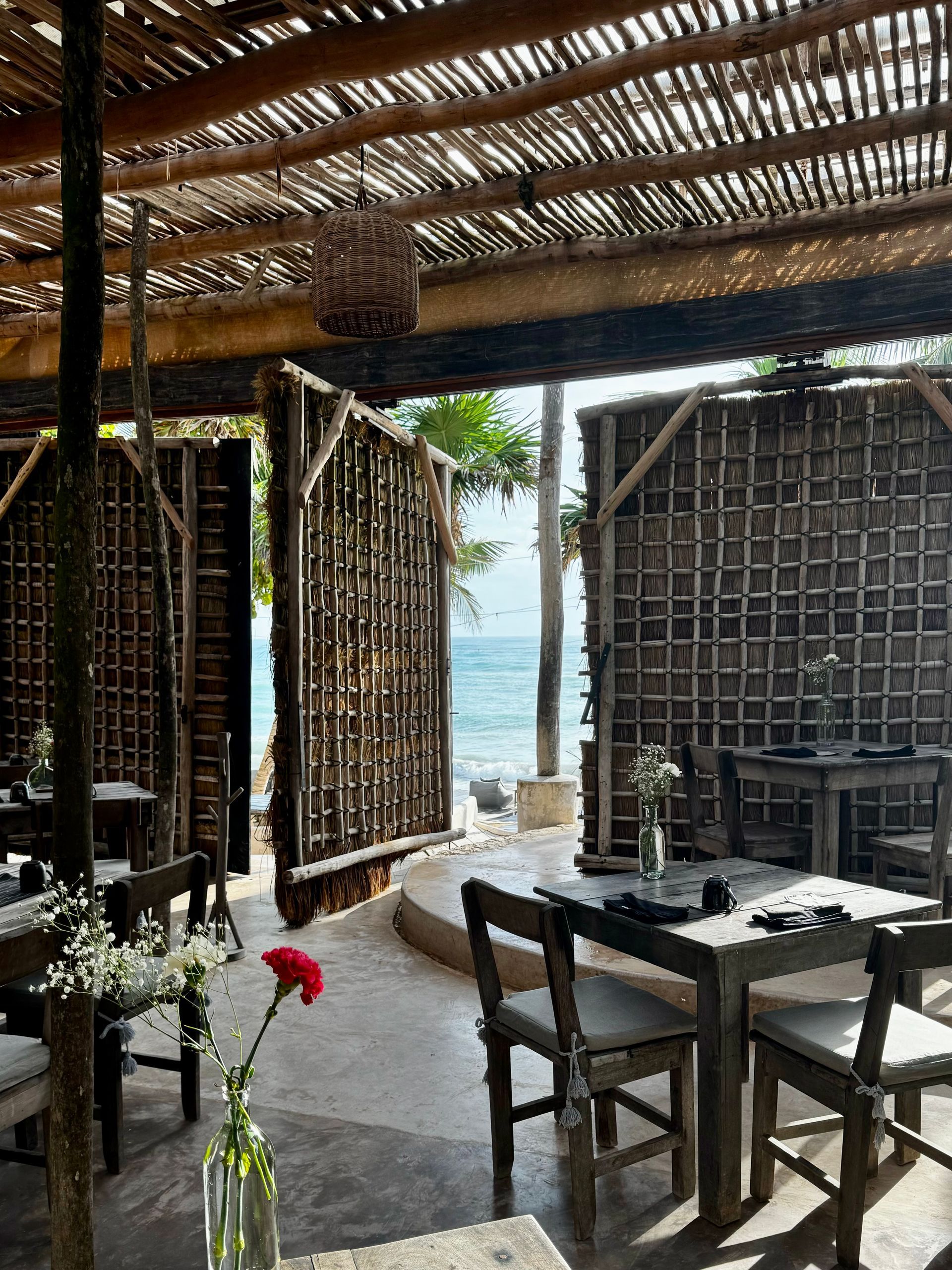Papaya Playa Beach Club's restaurant with tables and chairs and a view of the ocean in Tulum.