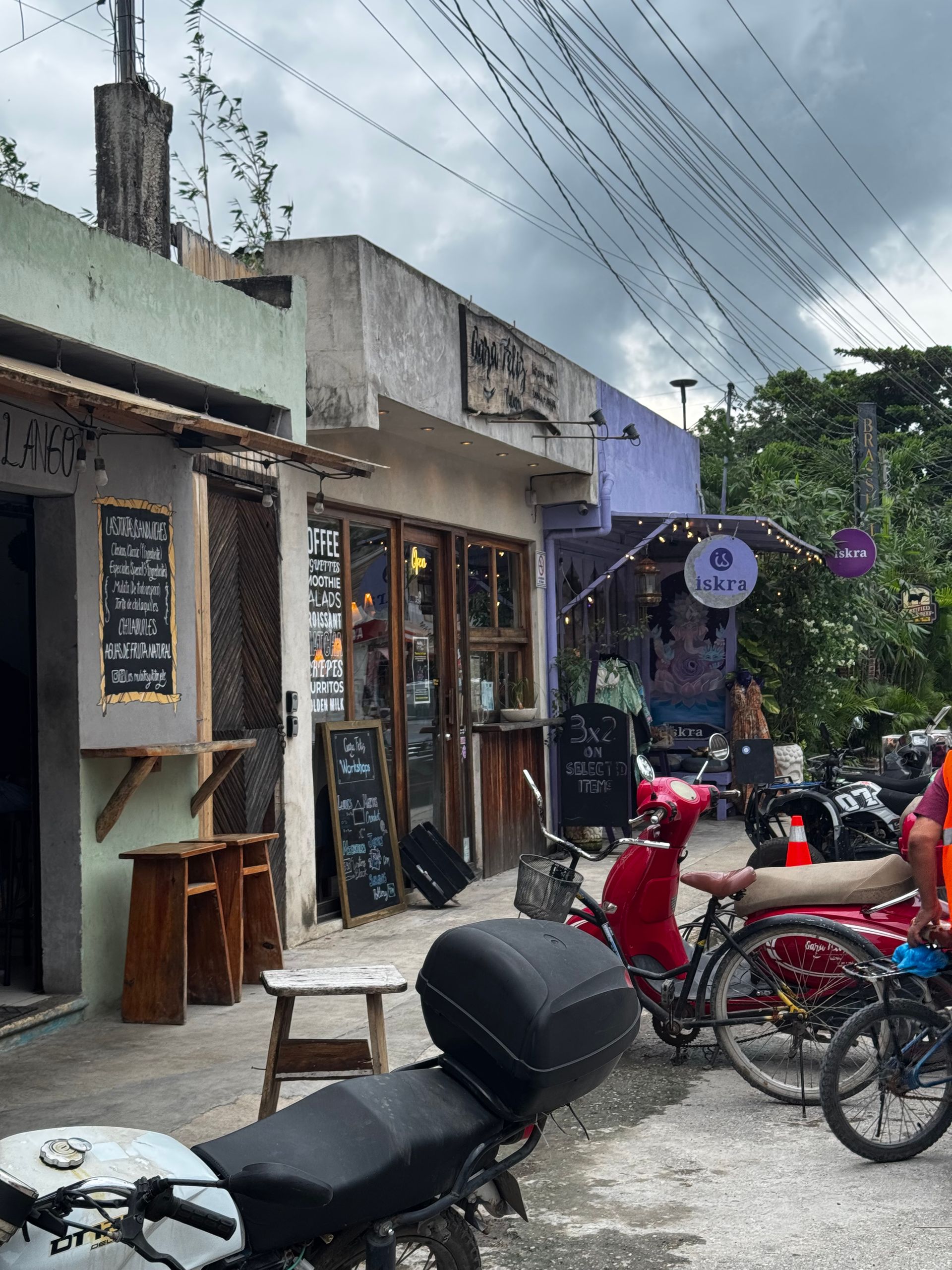 A row of buildings with motorcycles parked in front of them in Tulum Pueblo.