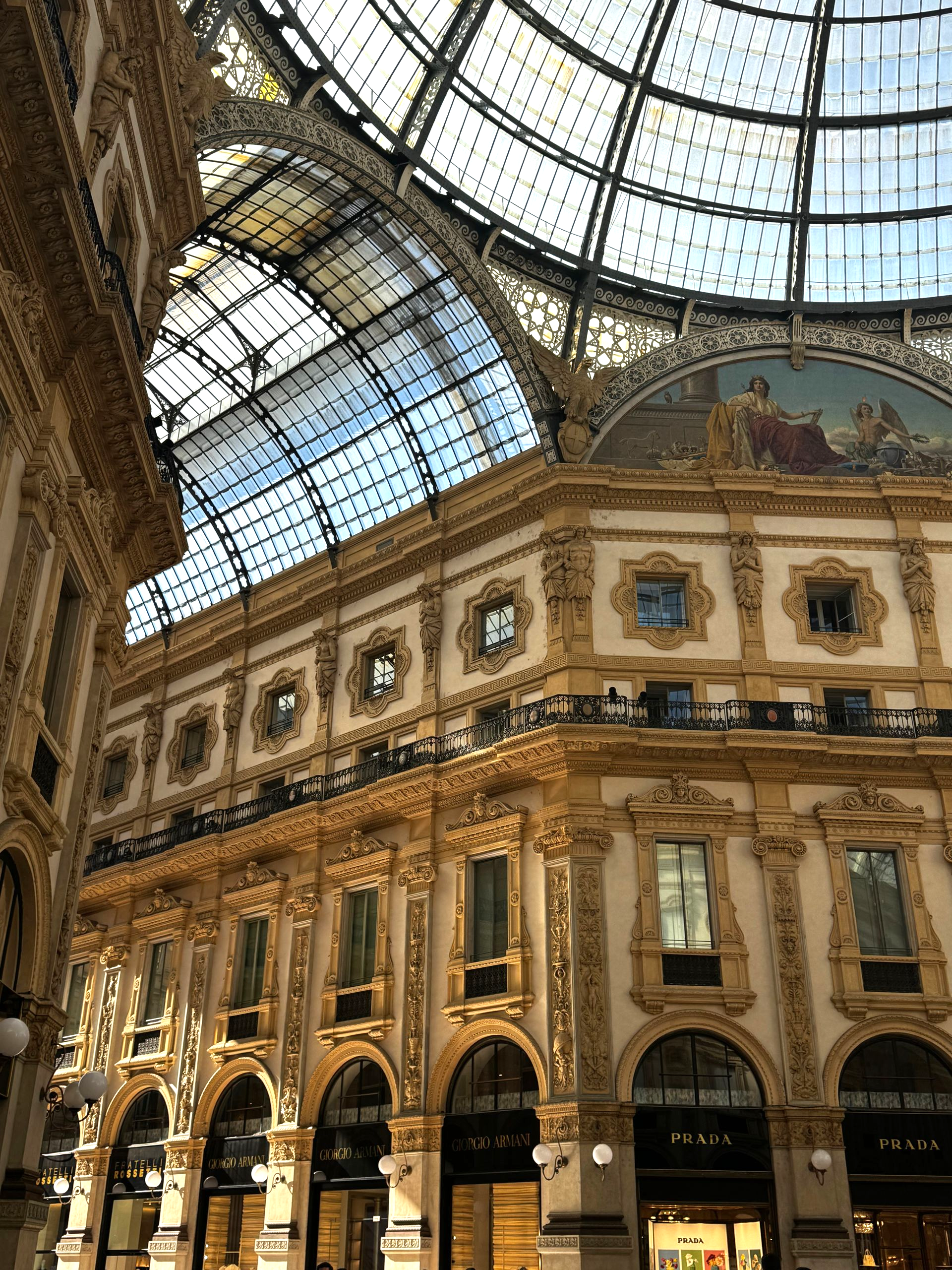 Ornate architecture, glass arched ceiling, Gucci storefronts in Milan, Italy.