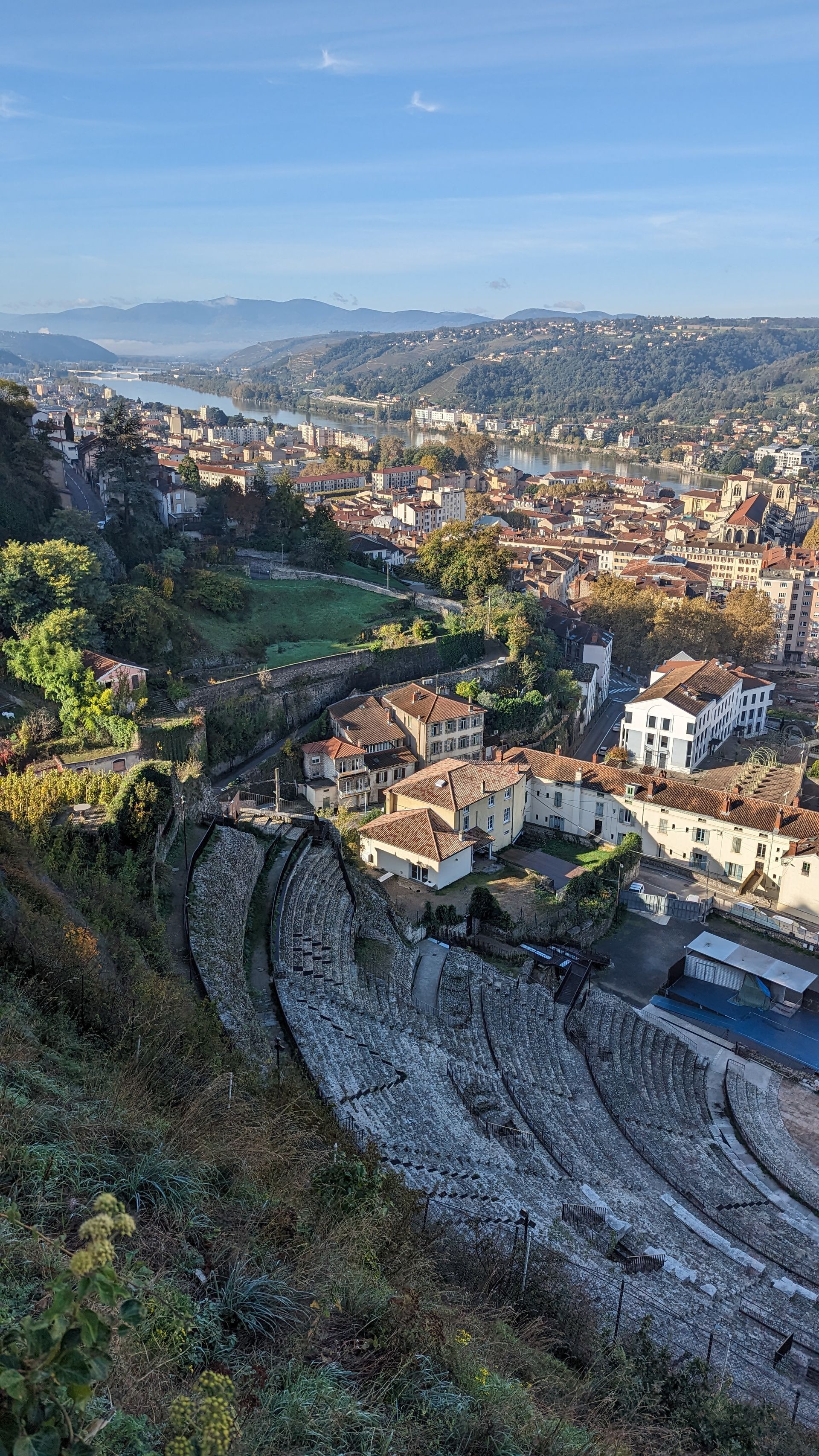 Cityscape with buildings and a river under a clear blue sky.