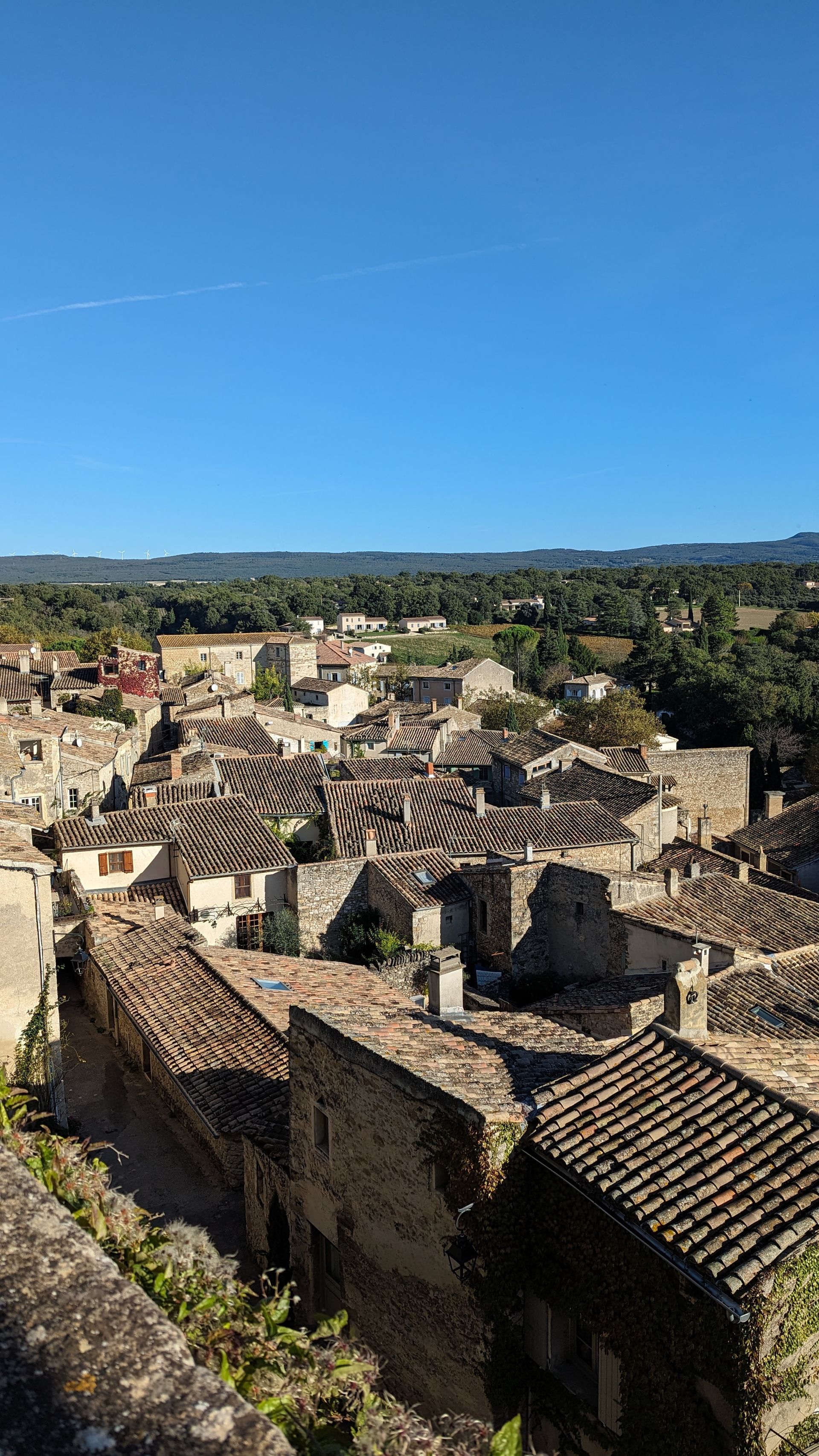 Overhead view of a European town with stone buildings, tiled roofs, and a clear blue sky.
