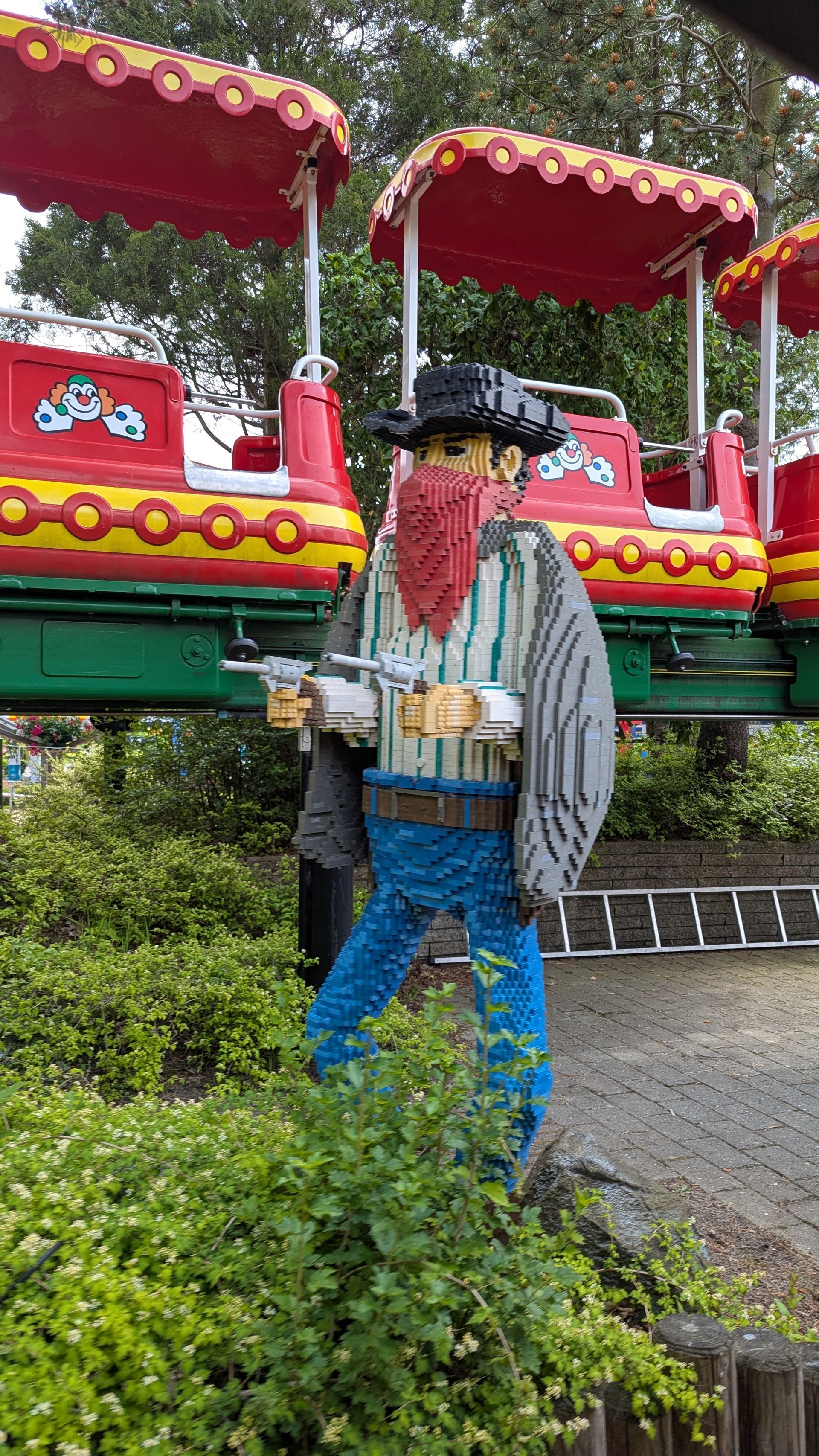 Lego cowboy figure with gun, near a red and yellow train on a green track.