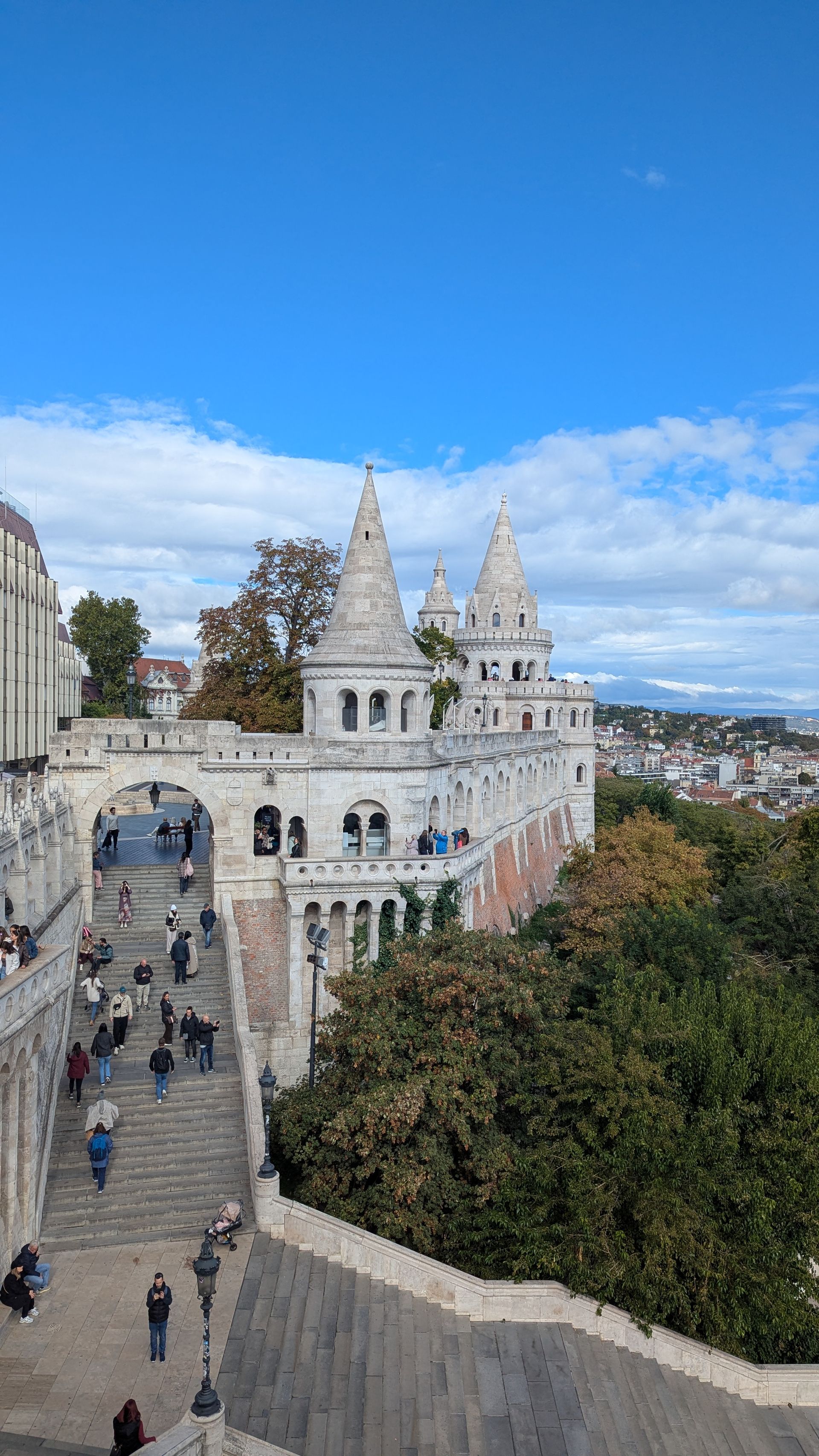 Fisherman's Bastion, Budapest, Hungary. White fairytale-like architecture against a blue sky, people on steps.