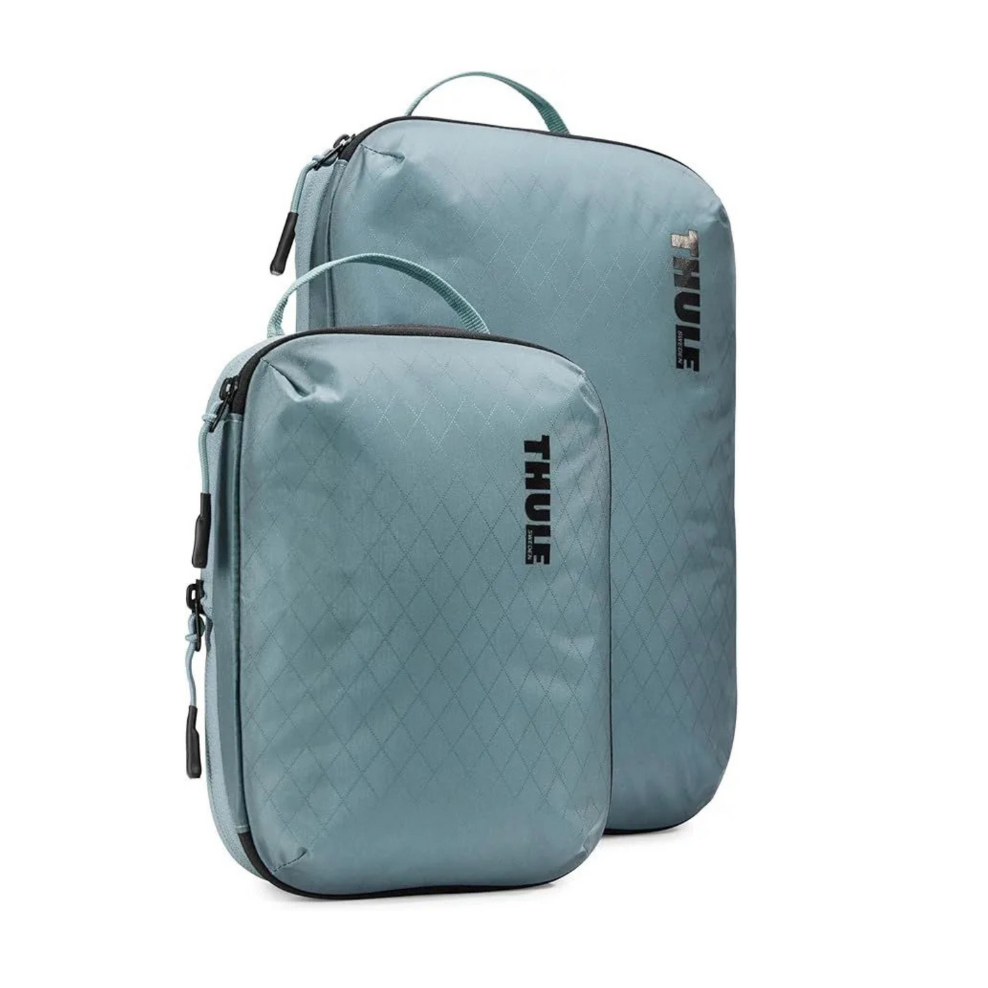Two blue thule bags are sitting next to each other on a white background.