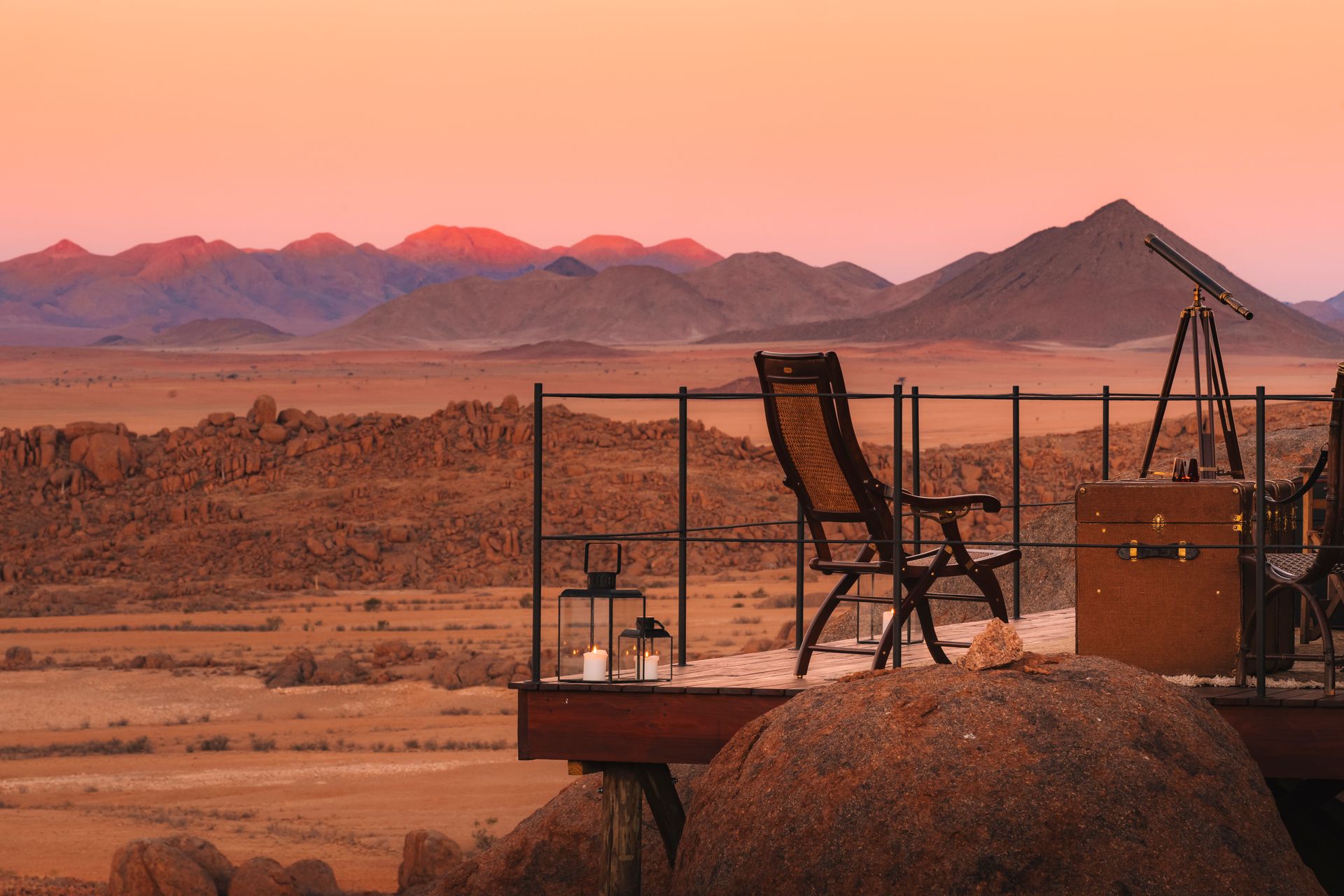 A balcony with chairs and a telescope at a desert camp in Namibia, Africa.