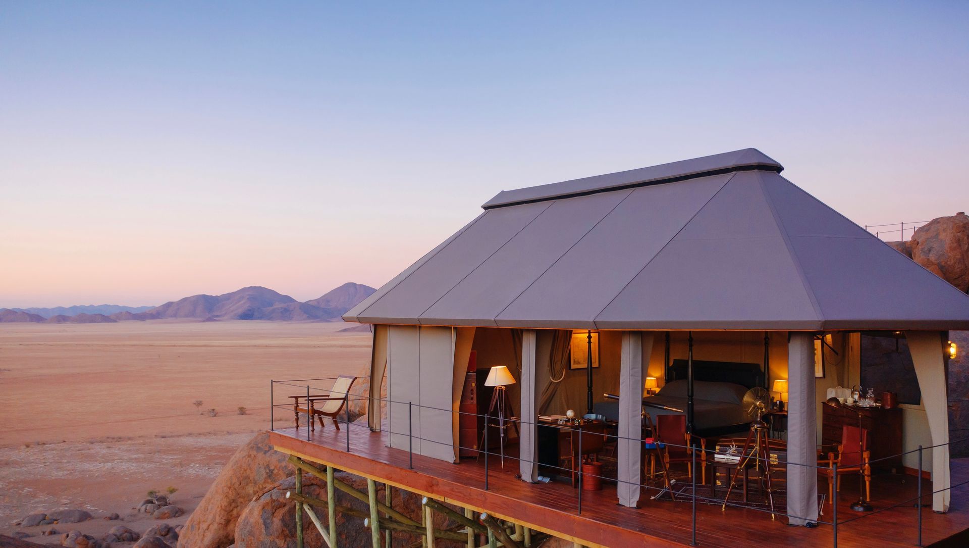 A large tent is sitting on top of a wooden deck at desert camp in Namibia, Africa.