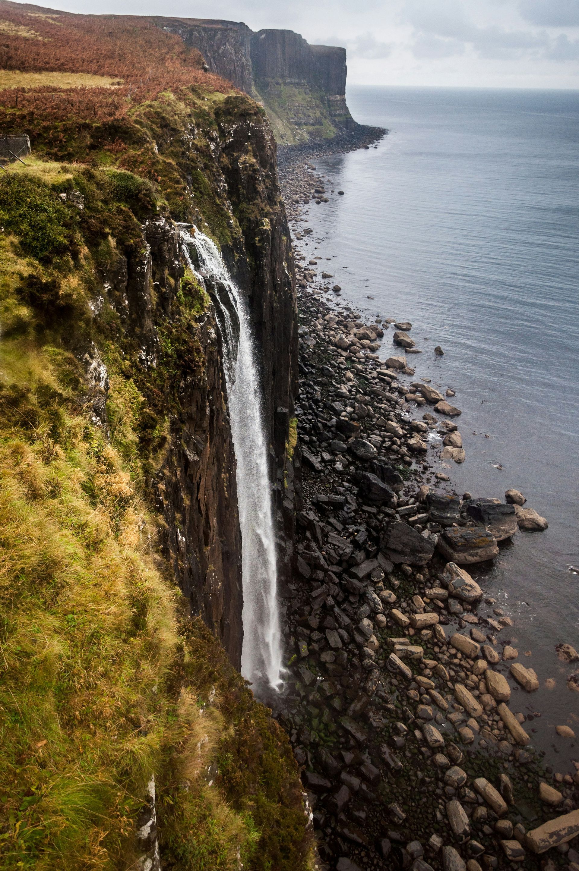Waterfall cascading down a cliff into the ocean on the Isle of Skye, Scotland.