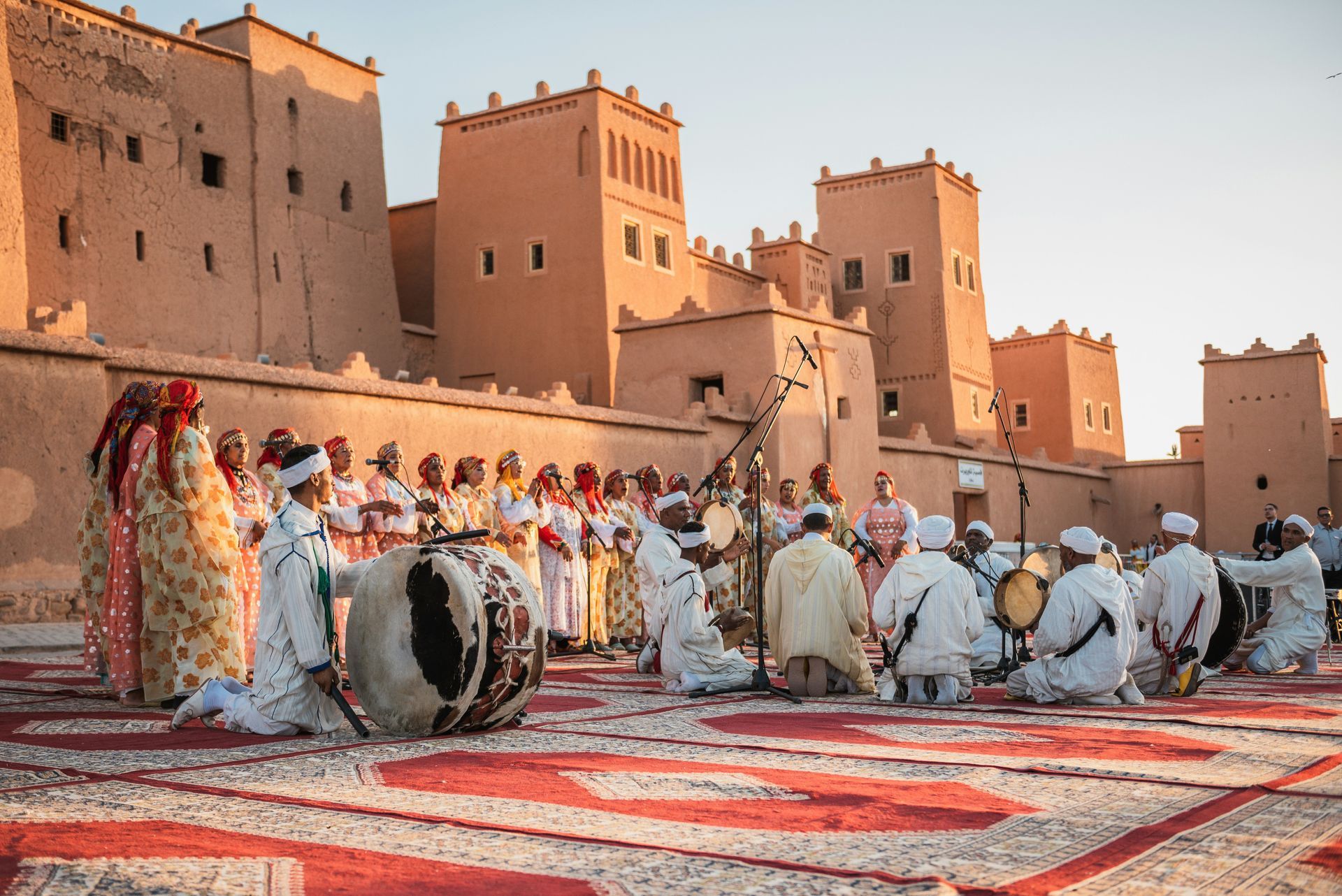 A group of people are playing drums in front of a castle in Ouarzazate, Morocco.