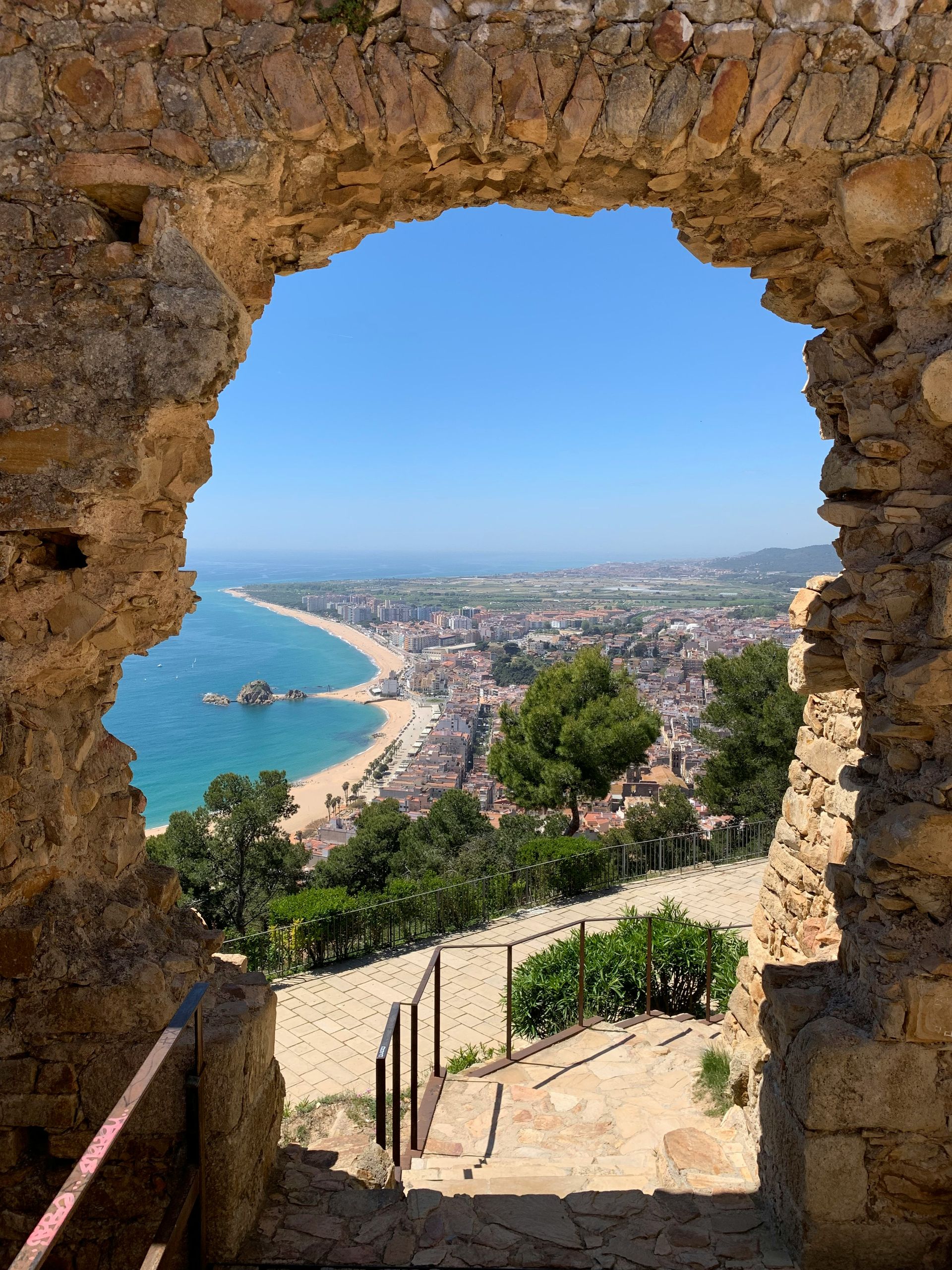 There is a view of the ocean through a stone archway in Blanes, Spain.